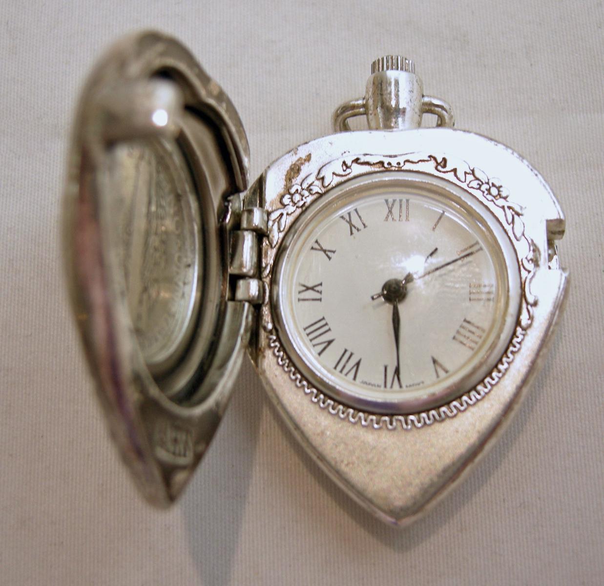 This vintage pendant watch has a heart shape with a 1938 US liberty dime in the center and opens to a watch.  Open and see the watch on the right and the other side of the dime on the left. This sterling silver pendant watch measures 1-3/4” x 1-1/8”