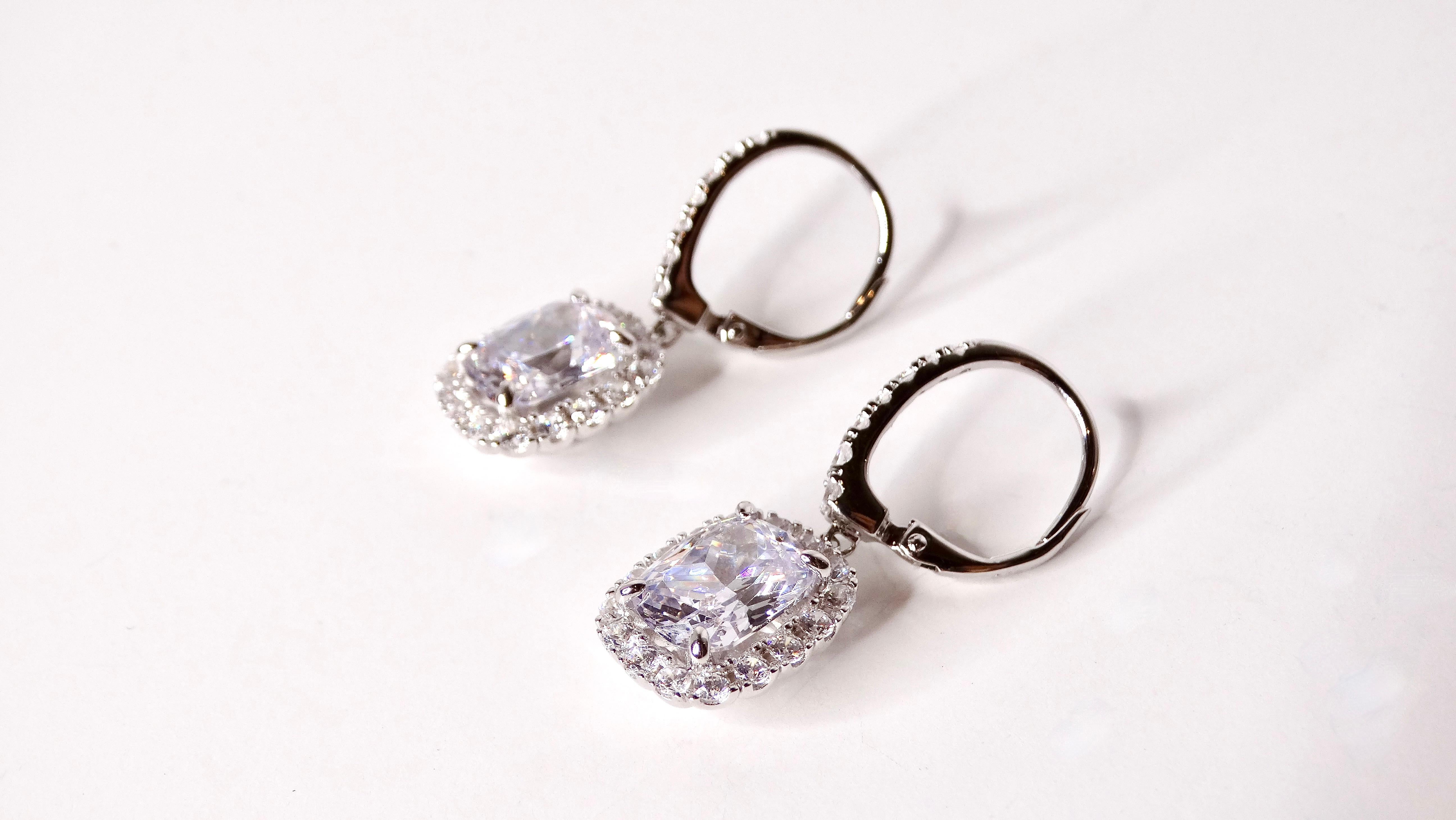 Rehaussez votre collection de bijoux avec ces exquises boucles d'oreilles vintage en argent sterling 925 incrustées de cristaux. Chaque boucle d'oreille est ornée d'un superbe cristal taillé en coussin qui brille comme un diamant, entouré d'un halo