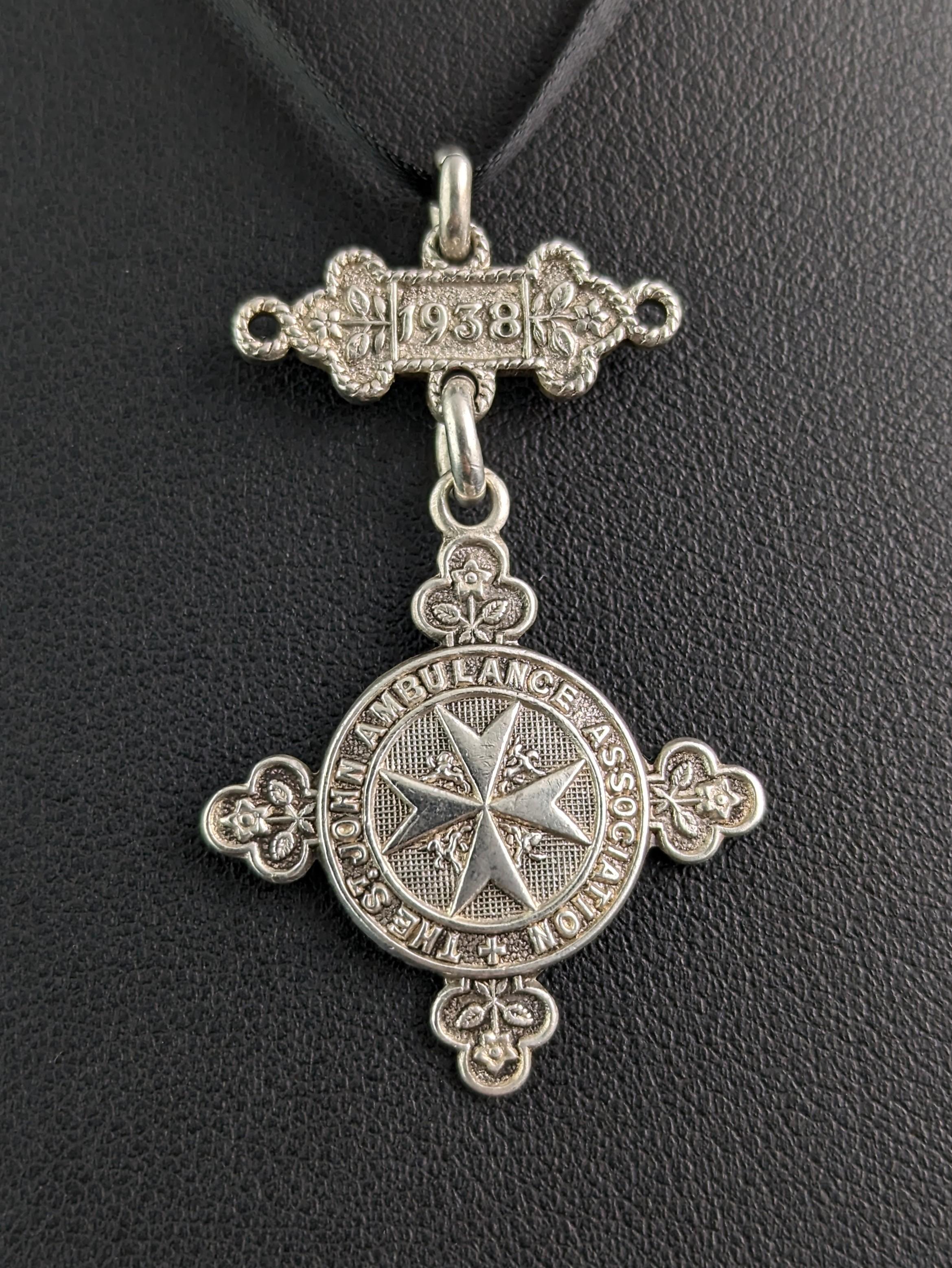 An interesting and decorative vintage silver fob pendant or medallion.

This attractive little fob is formed of two sections, the top bar section dated 1938 and the suspended fob, a circular shape with four trefoils bordering it, reading, The St