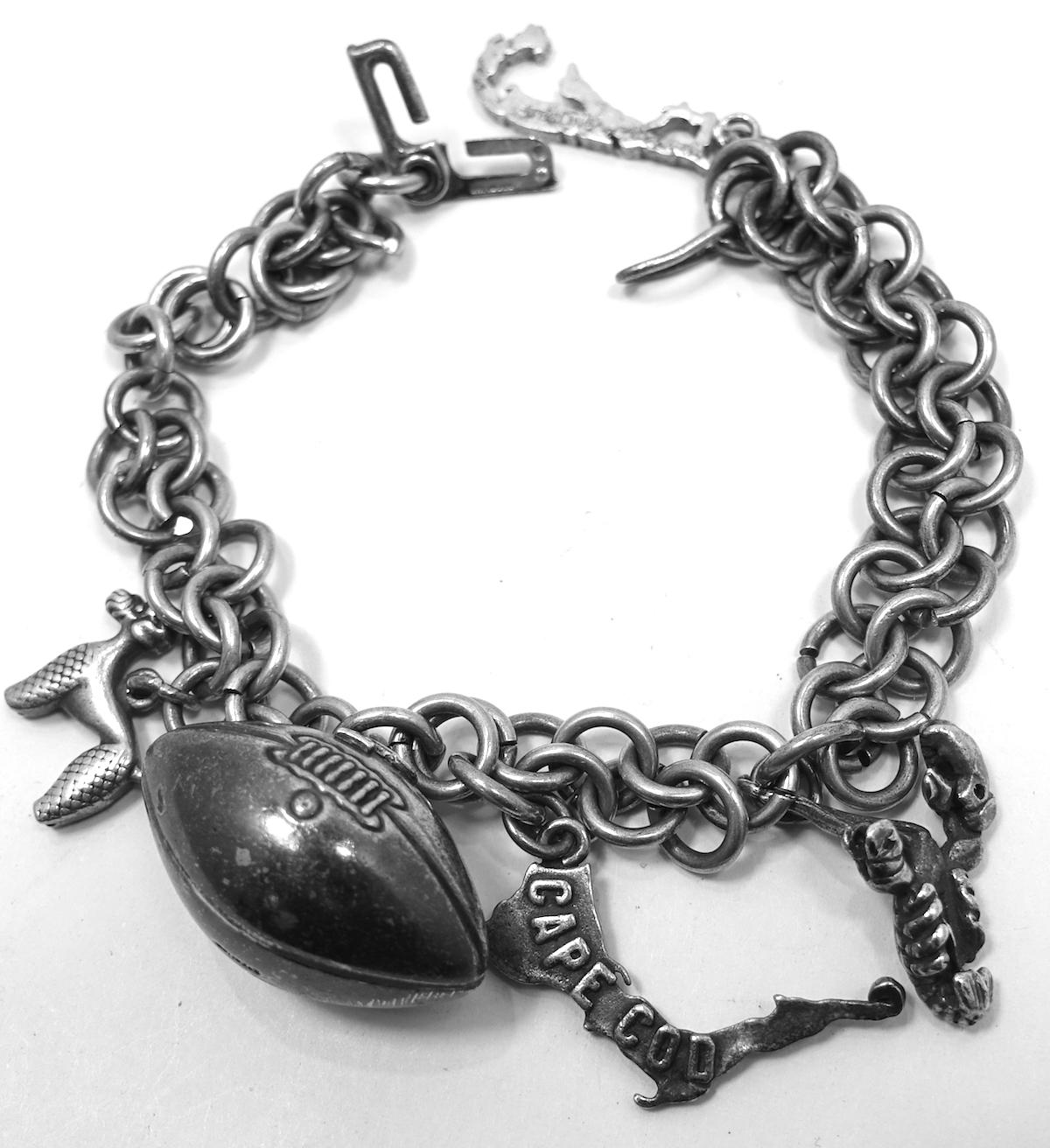 This vintage bracelet has 5 charms on a sterling silver twisted link bracelet. The charms consist of a football that measures 1” x 5/8”, a lobster, a Cape Cod map, a Bermuda map, and a poodle.  The bracelet is 7”. In excellent condition, this