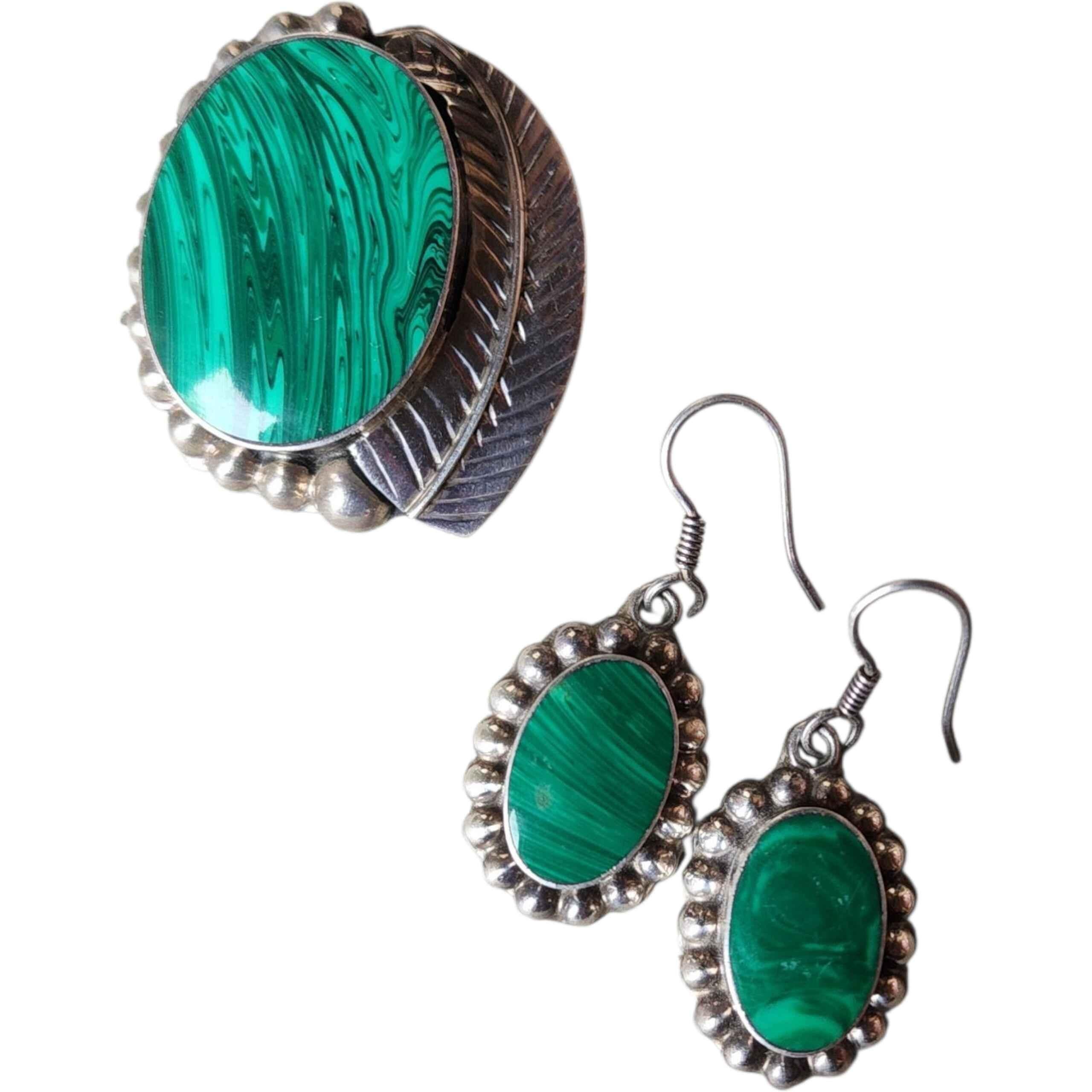 Este exquisito conjunto de joyas vintage incluye un precioso broche de plata de ley hecho a mano y unos pendientes colgantes a juego, cada uno de ellos con cabujones de malaquita natural de color verde intenso que muestran motivos clásicos en