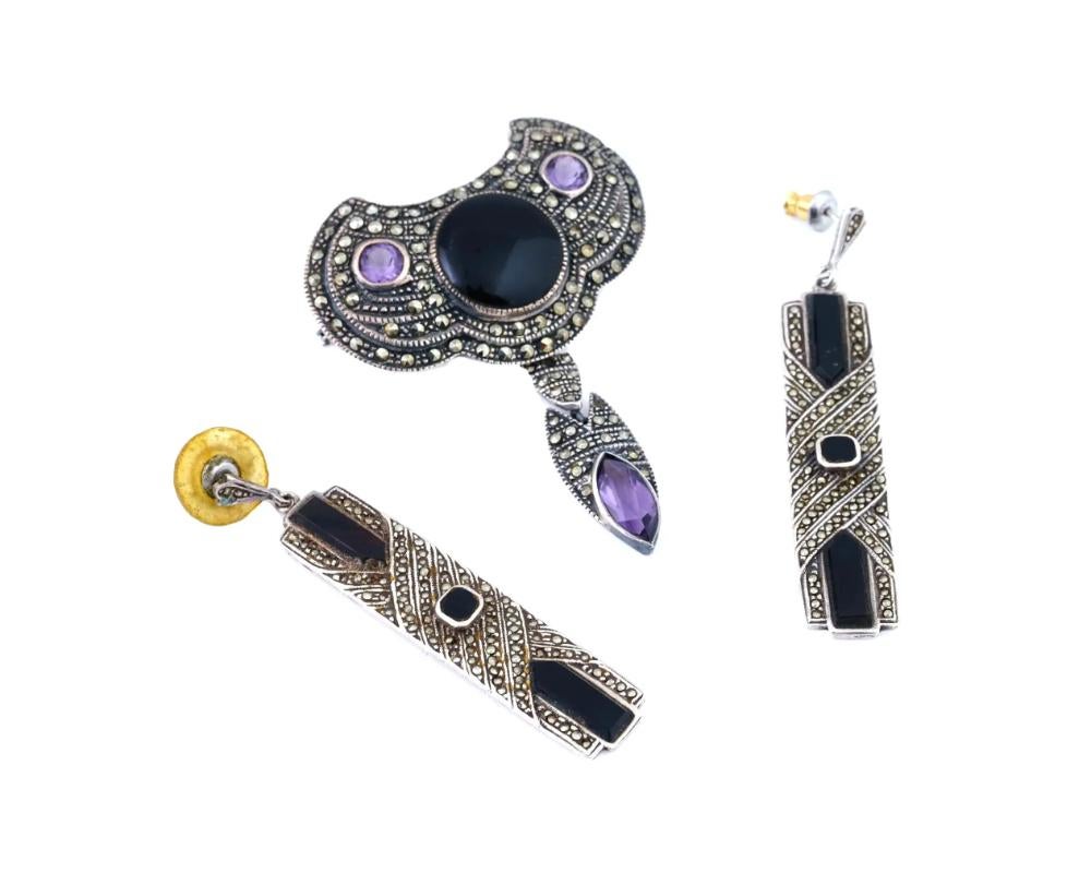 A vintage Mexican sterling silver two-piece jewelry set, a large pin brooch and a pair of dangle earrings. Geometrical design. The items are embellished with polished marcasites and cut amethyst stones. Each item is marked 925 on the backside. Total