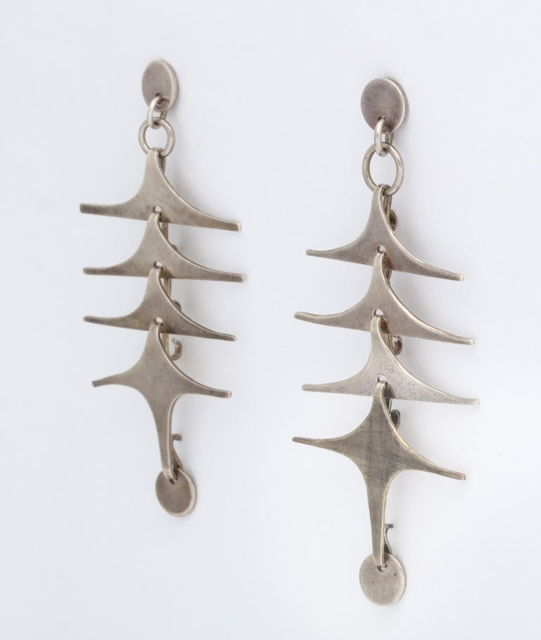 Reminiscent of Calder or the wonderful jewelry of Art Smith, these artist made sterling silver earrings by Mary Ann Scherr are six cascading triangles appearing like airplanes or abstract birds in flight. The top and bottom are defined with a
