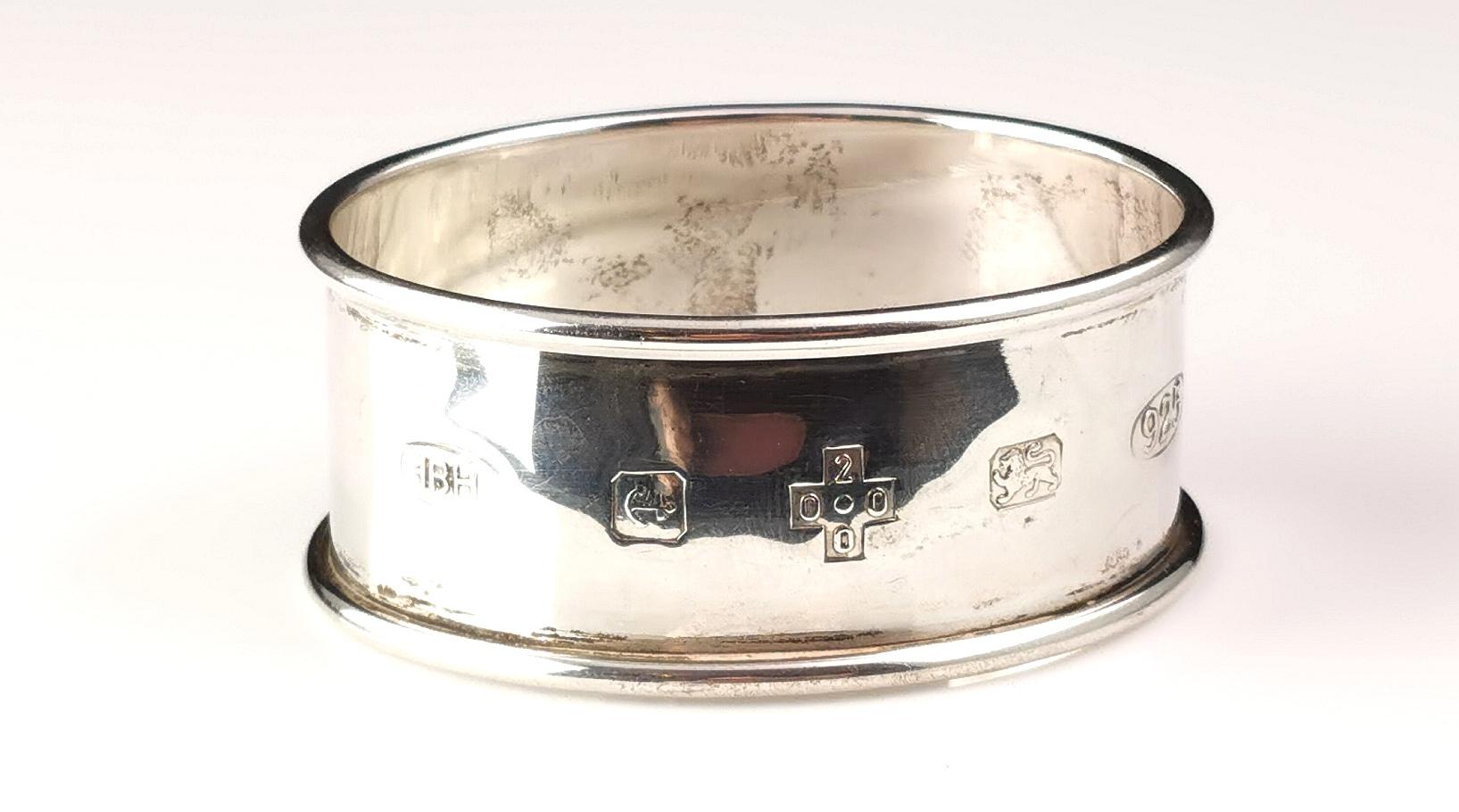 A stylish vintage sterling silver napkin ring.

It is a plain oval shaped napkin ring with a polished finish and with hallmarking to the front including the millennium mark.

It is fully hallmarked for sterling silver, Birmingham assay office, 2000,