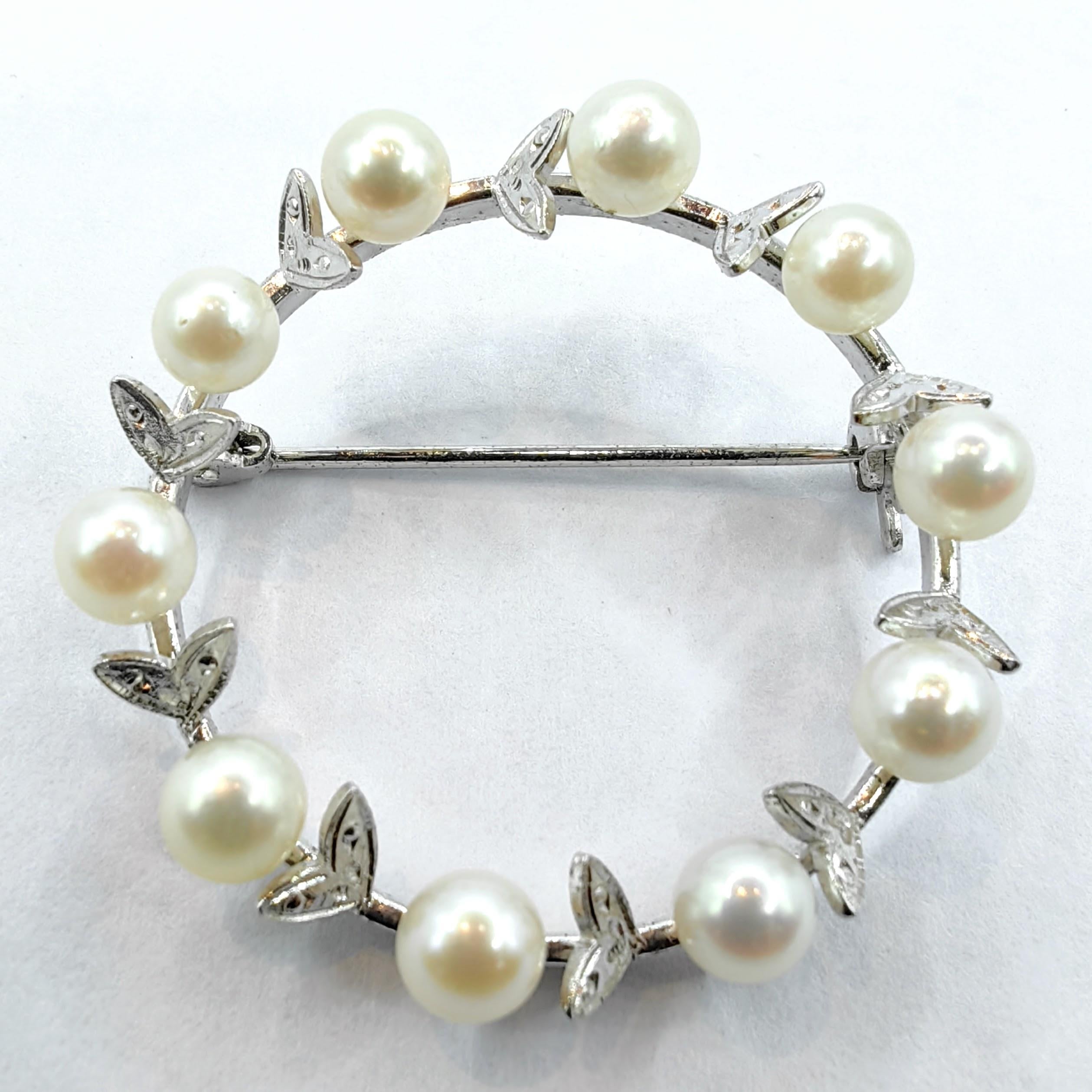 Elegance meets timeless beauty in this exquisite vintage sterling silver wreath brooch, adorned with ten luminous white freshwater pearls measuring approximately 4.5-5.0mm each. The pearls are carefully set within a delicate sterling silver