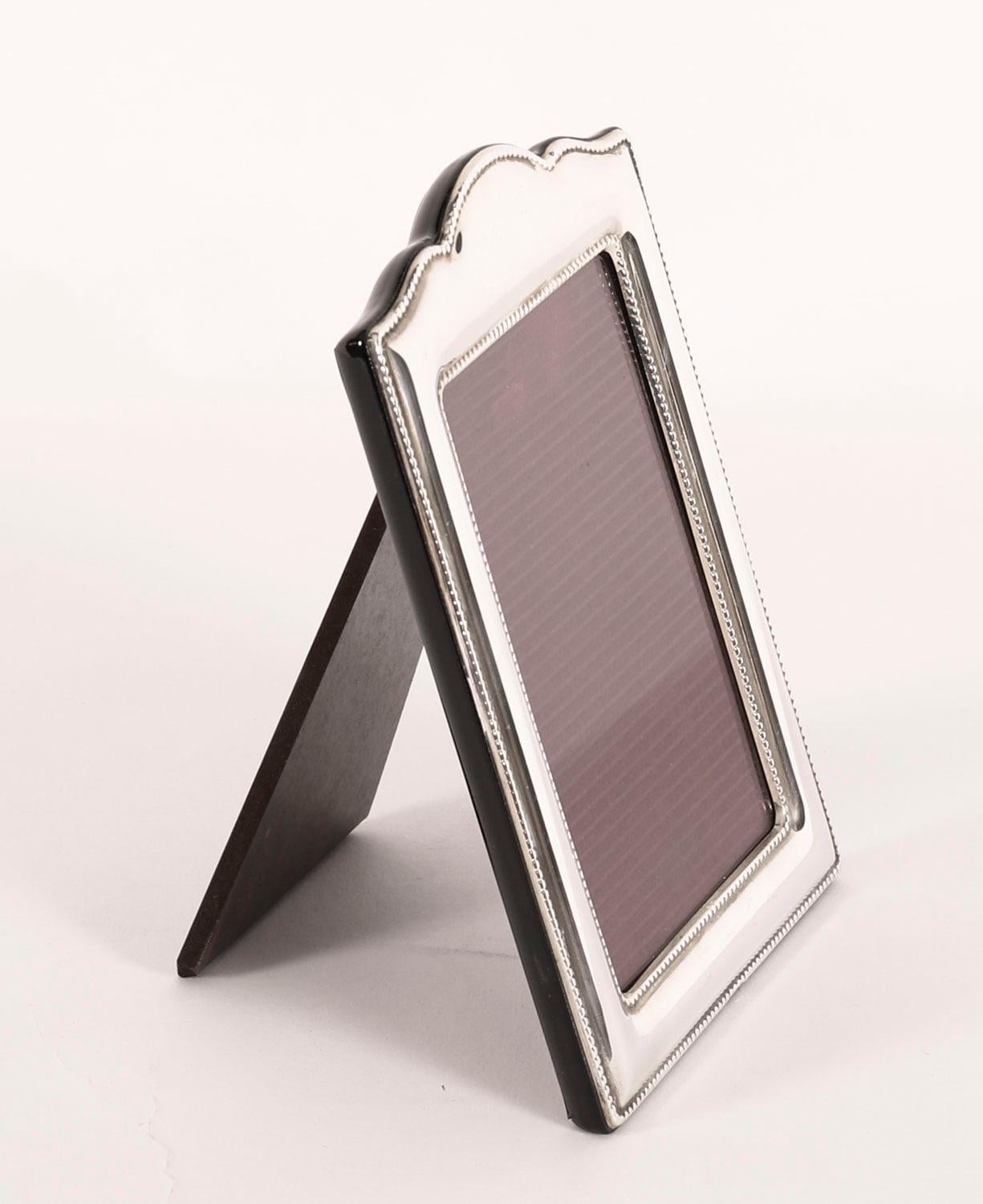 Un superbo portafoto decorativo d'epoca in argento sterling con marchio di fabbrica della fine del XX secolo.

Bellissima cornice rettangolare da ritratto con piano sagomato e decorato con bordi in rilievo, con fondo a cavalletto in noce