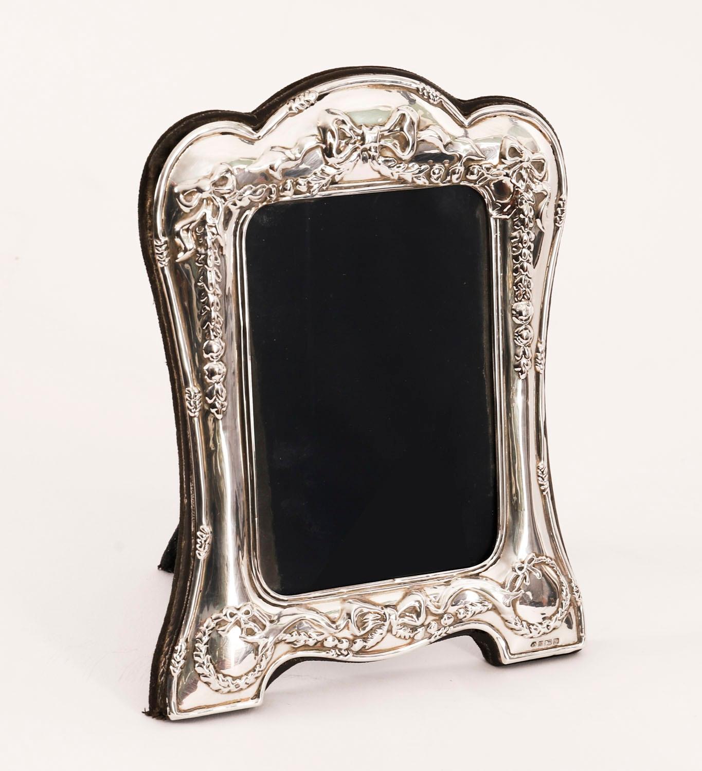 Superba cornice decorativa neoclassica in argento sterling, con marchio di fabbrica RBB e punzoni di Sheffield 1990.

Bellissima cornice rettangolare con ritratto, decorata con nastri legati e campanelle blu e con il retro del cavalletto in velluto