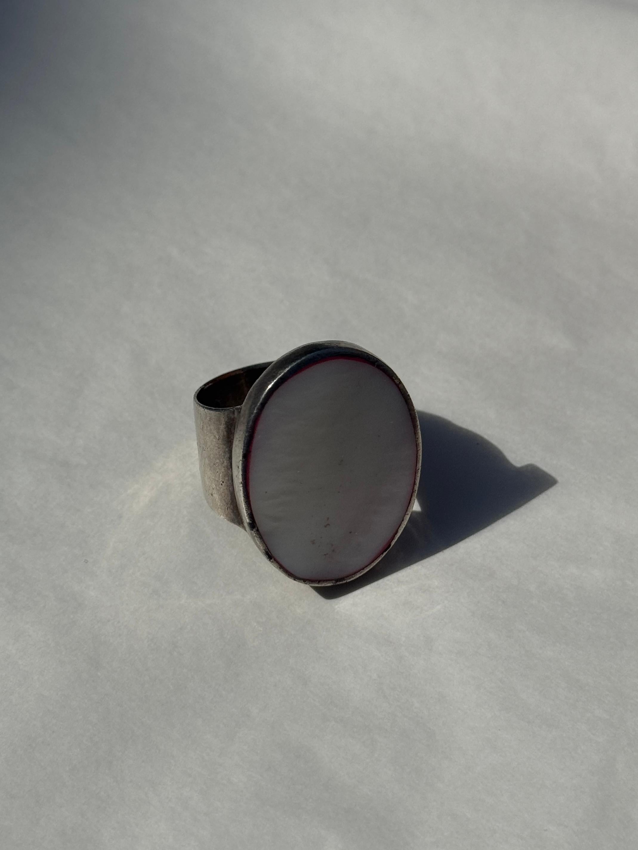 Artisanal ring in 925 sterling silver with a bold yet minimal design, featuring a wide band and a large oval inlay with a mother-of-pearl effect, set in a smooth bezel. The inlay displays a pearly white tone with natural-looking veining and a soft