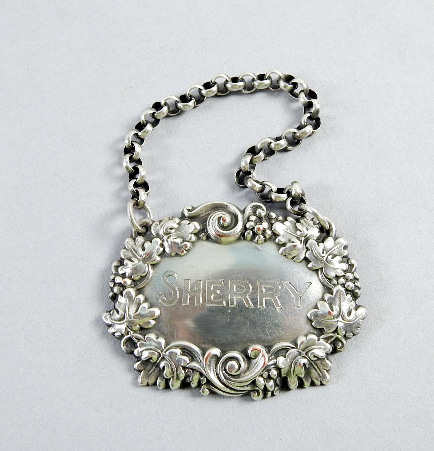 Vintage silverplate over copper hanging liquor tag engraved Sherry. Grape and grape leaf repousse design, marked Ster., however under lying copper can be seen in a couple spots, surface scuffing.