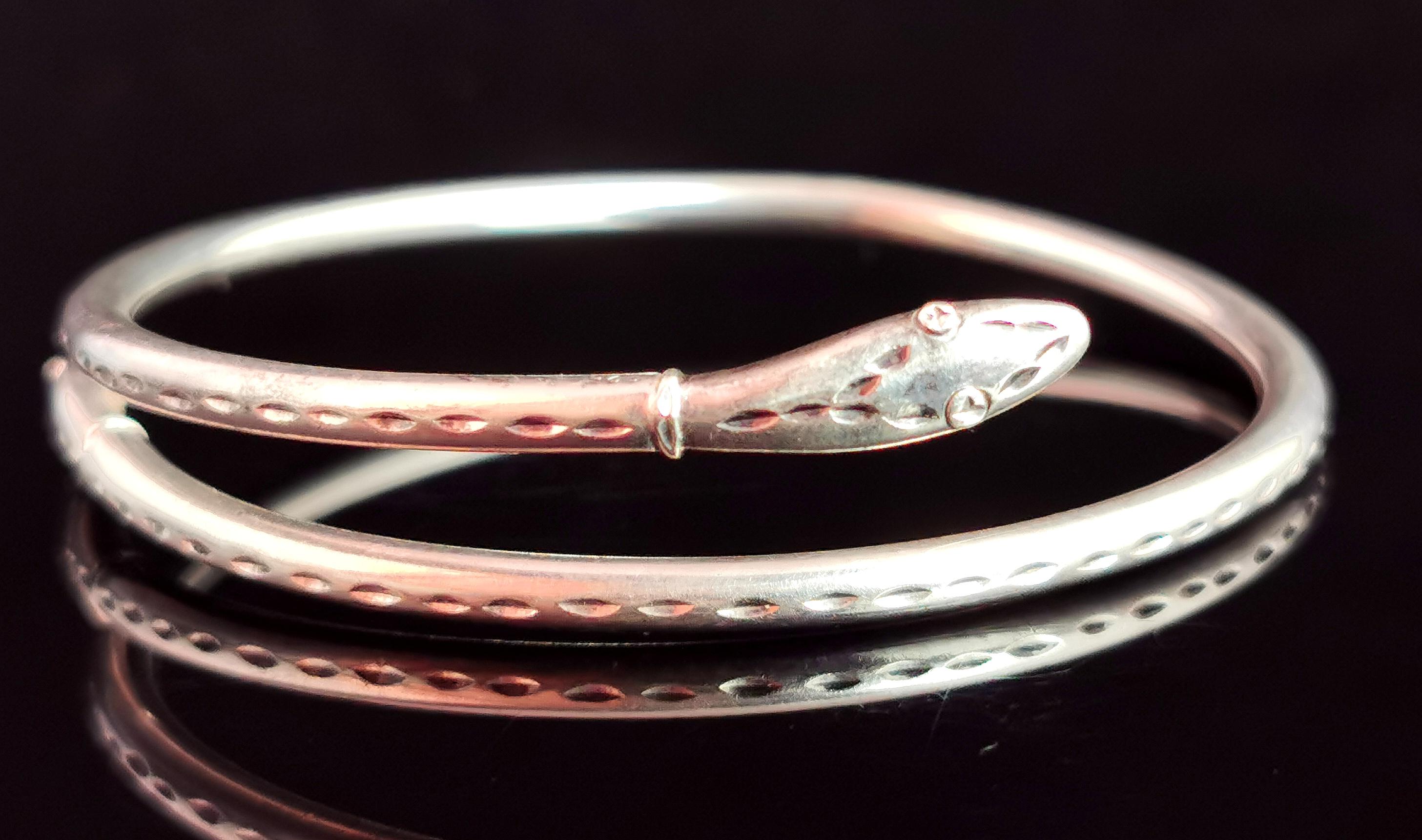 A sweet vintage sterling silver snake bangle.

It is a cross over bangle with two snake heads either side, the body of the bangle is made up from a slender sterling silver band, lightly engraved.

Designed in an Art Deco style, reminiscent of the