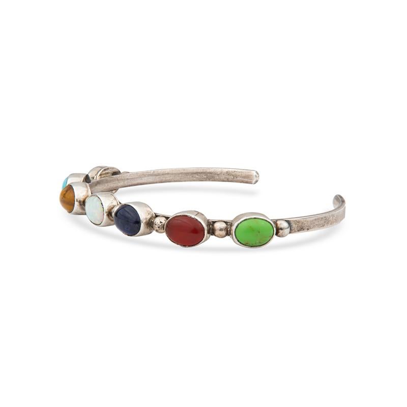 This dainty vintage sterling silver cuff features seven bezel set stones including hematite, turquoise, tiger's eye, gaspeite, and carnelian. Wear alone or layer with your other bracelets. It measures approximately 6.90mm and weighs 13 grams.