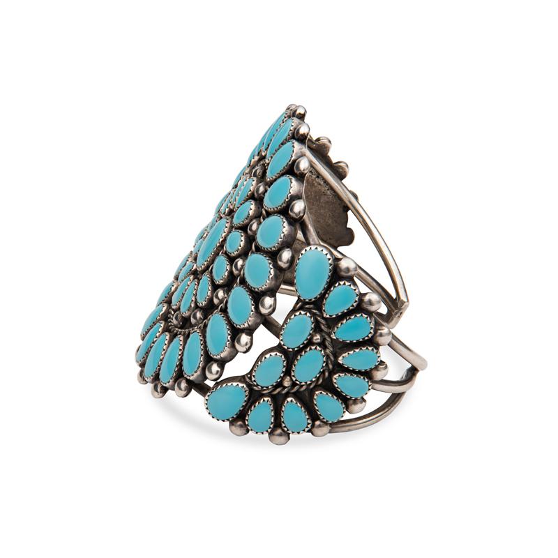 This vintage sterling silver cuff features large pieces of turquoise. It makes a great statement piece! The cluster was developed by Zuni artists in the 1920's. They used natural gemstones such as turquoise, coral, and jet and arranged them into