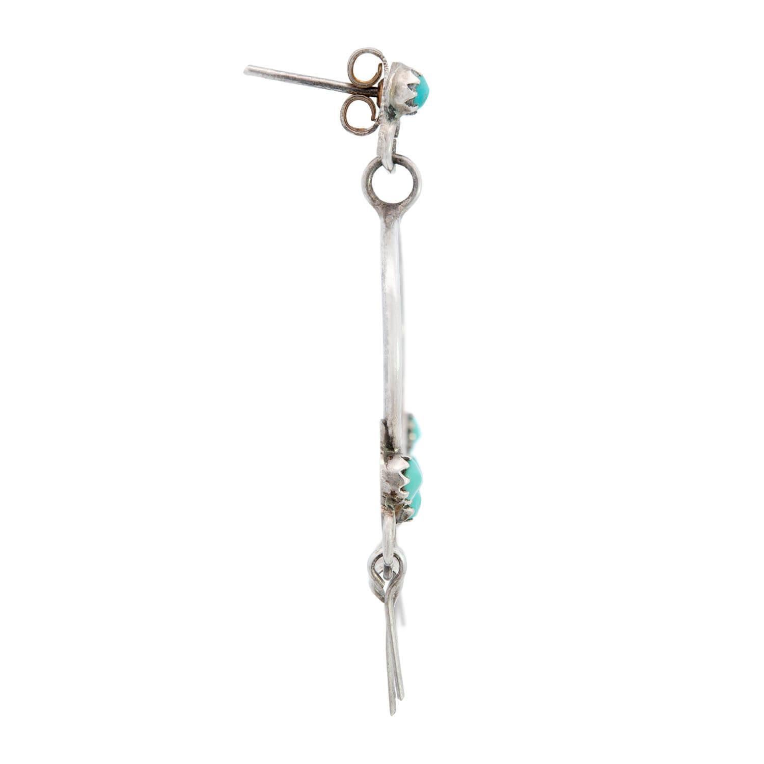 A gorgeous pair of turquoise hoop earrings from the Vintage (ca1960s) era! Crafted in sterling silver, each earring begins with a small turquoise cabochon surmount. The turquoise stone is held within a prong-setting. The earrings then feature a