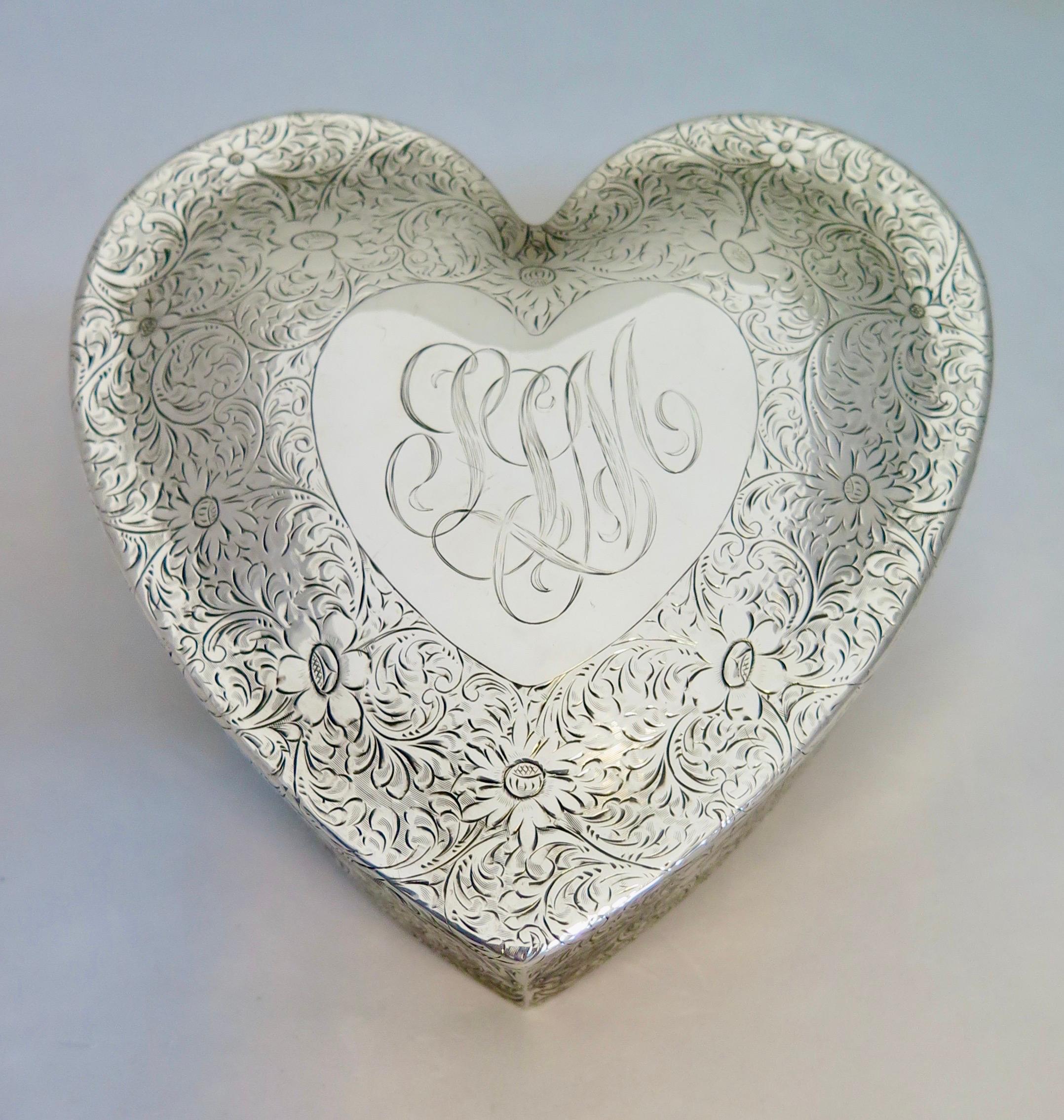 This vintage rare sterling silver heart shape Valentine jewel box dates from the early 20th century. The sterling jewel box is beautifully chased with an overall motif of detailed scrolls and flowers. The floral patterns dramatically heighten a