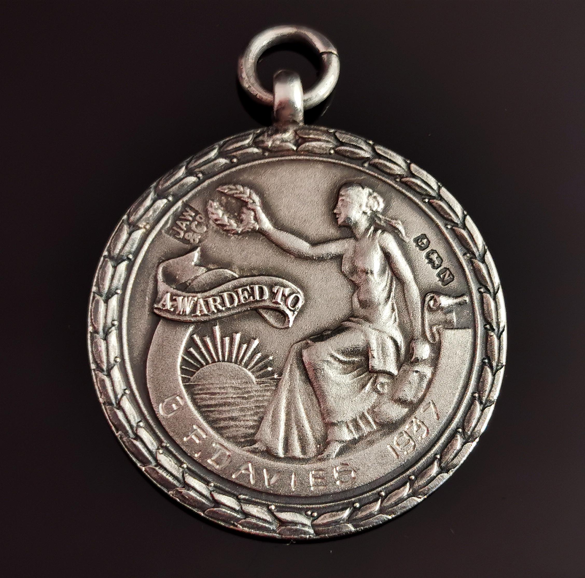 A rare vintage sterling silver watch fob pendant.

Watch fobs were traditionally attached to Albert chains and were used as commemorative pieces, awards and also produced as medals.

This is a rare vintage fob, very well designed on each side with