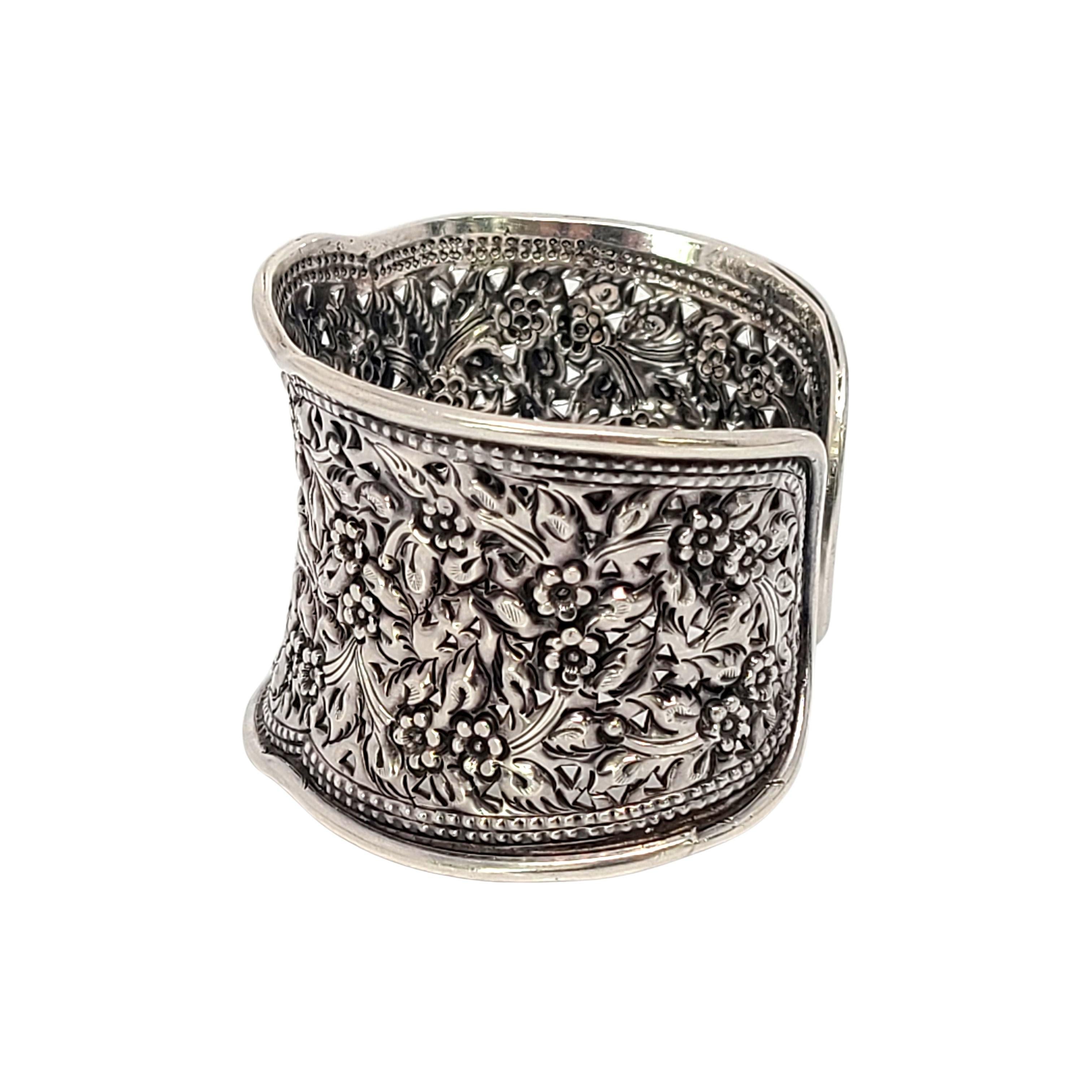 Breites Manschettenarmband aus Sterlingsilber mit Blumenmuster.

Schönes repoussiertes Blumen- und Blattmuster mit kleinen Ausschnitten.

Maßnahmen ca. 6 1/2 