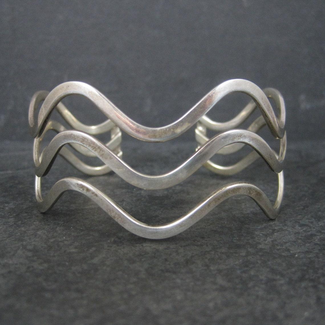 Este precioso brazalete vintage es de plata de ley.

Mide 2,5 cm de ancho.
Tiene una circunferencia interior de 7 pulgadas, incluido el hueco de 1 pulgada.
Peso: 27.3 gramos

Marcas: 925

Estado: Excelente