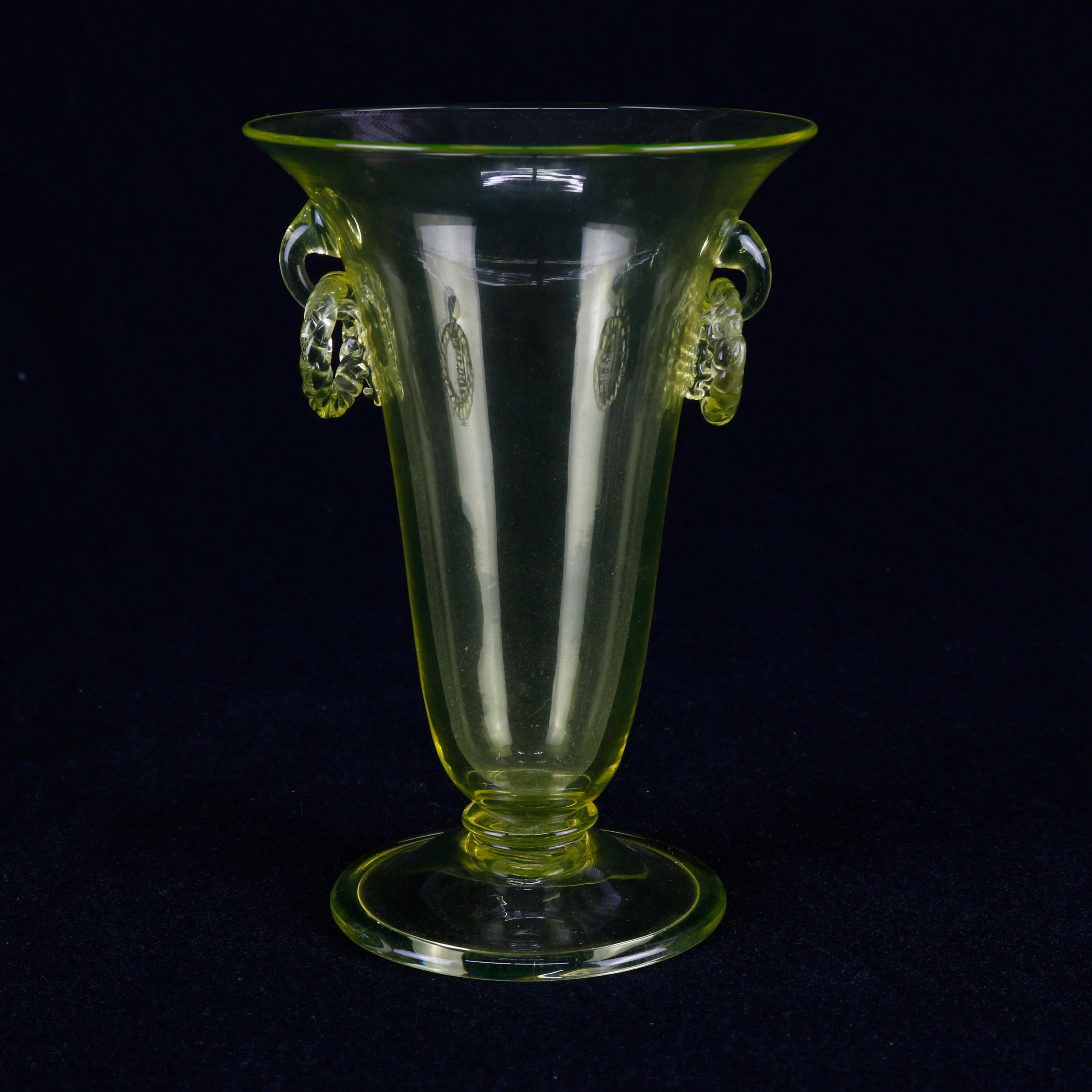 A vintage Steuben handcrafted art glass vase offers amber yellow flared form with flaking ring handles and seated on round foot, unsigned, 20th century.

Measures: 6