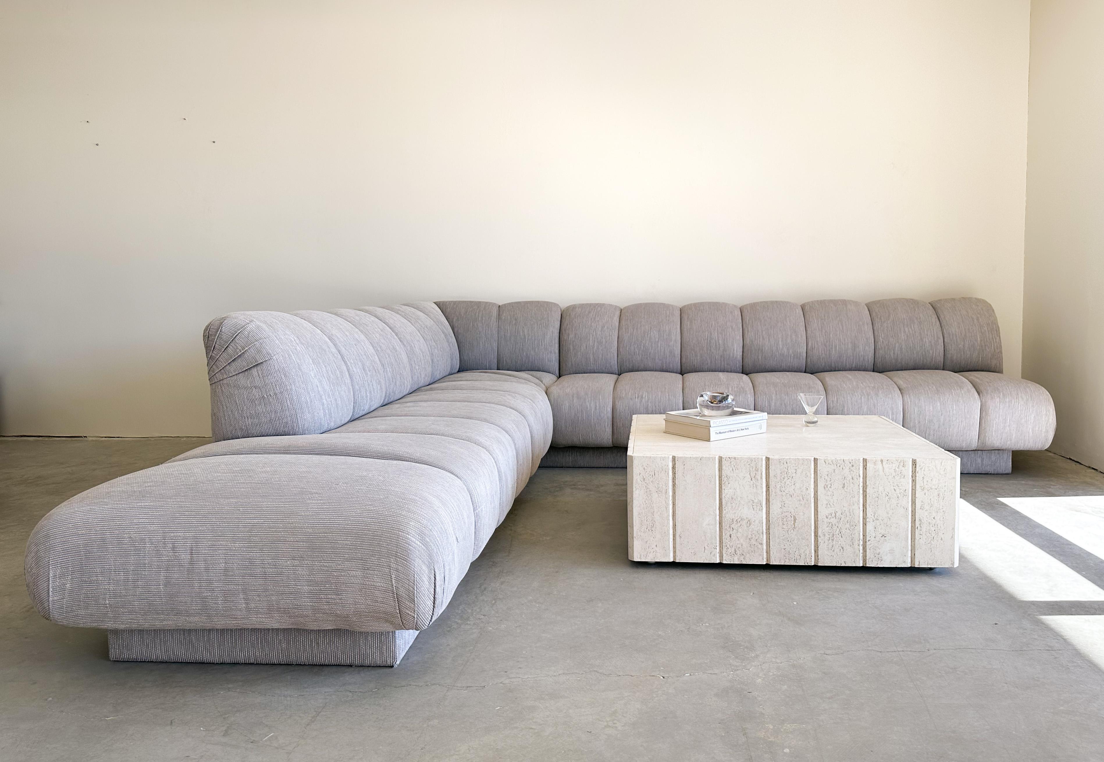 Vintage Steve chase sectional sofa.

The sofa comes in 2 sections. The fabric has a texture and is in a stripe pattern.
I think it will look great reupholstered in a boucle or a high pile cotton velvet. 

Color: Light bluish grey