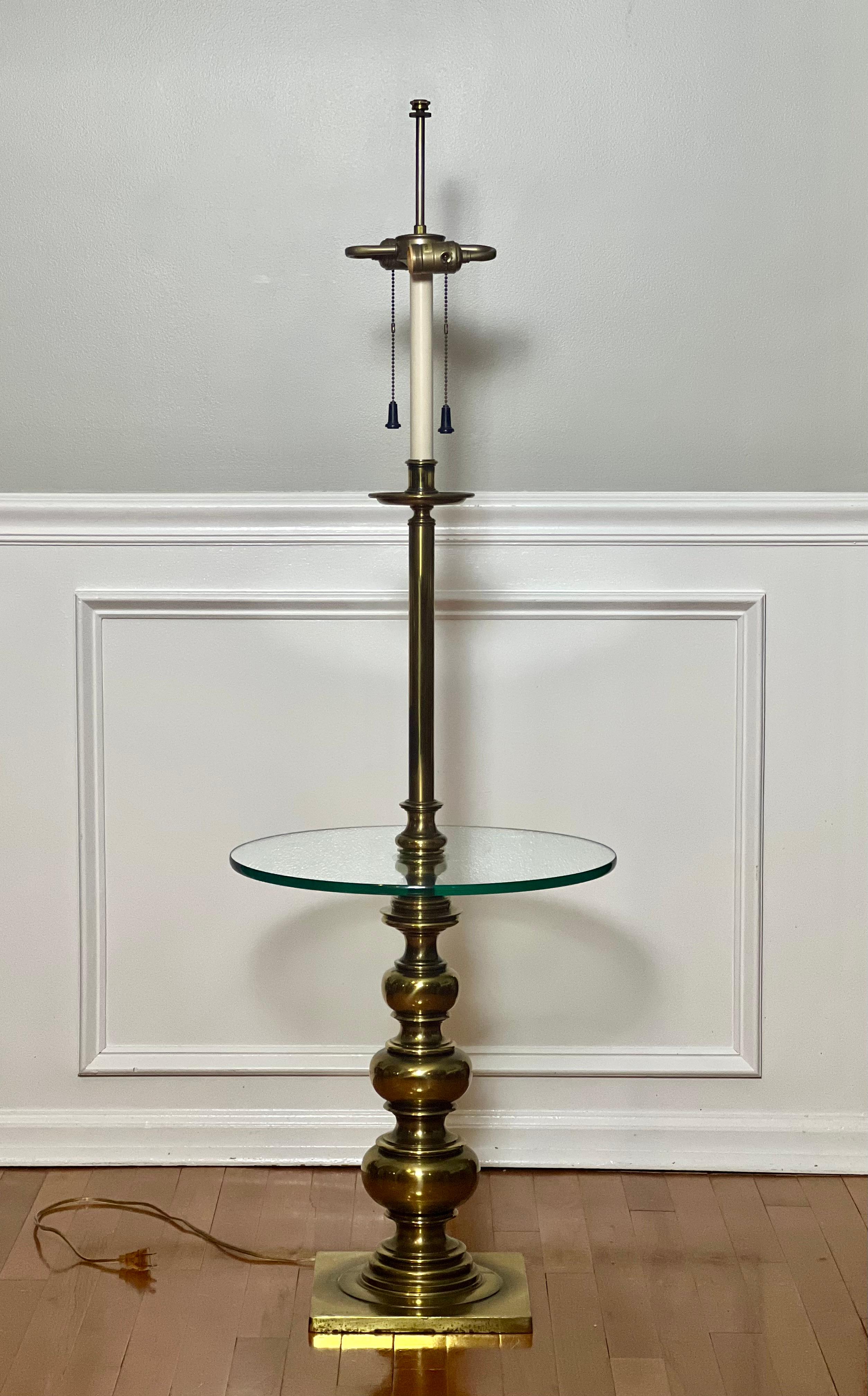 Elegant lampadaire vintage en laiton avec table en verre par Stiffel, circa 1970. La lampe comporte deux lumières avec des chaînes de traction et fonctionne de manière indépendante. Le corps est en laiton lourd avec une finition en laiton bruni et