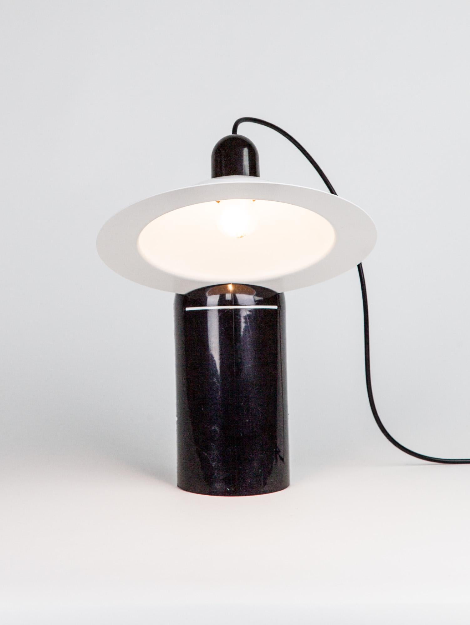 Playful Lampiatta table lamp designed by De Pas D'Urbino Lomazzi in 1971 for Stilnovo. Original vintage table lamp from the 1970s with a white aluminium shade and a heavy black plastic base. The clever design of the shade can be positioned by