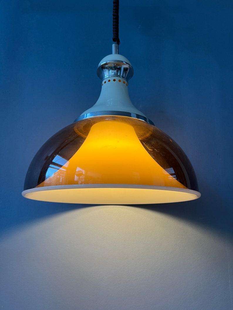 Mid century Stilux Milano space age pendant lamp with double plexiglass shade. The lamp consists of an acrylic glass copper coloured outer shade and a white inner shade. The height of the lamp can be adjusted with the rise-and-fall system. The lamp