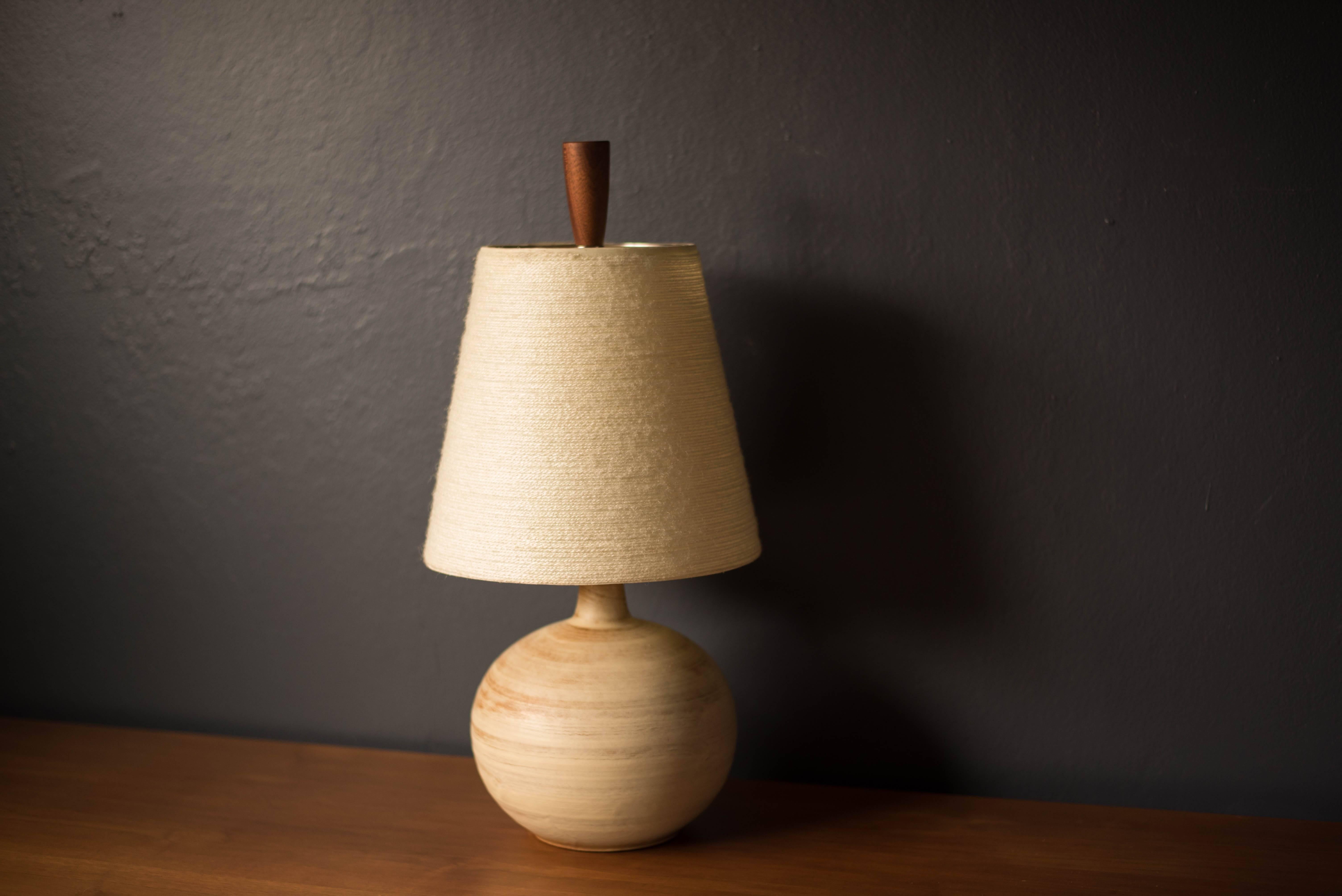 Mid-Century Modern ceramic table lamp, circa 1960s. This piece displays a neutral tone matte finish and is accessorized with a walnut finial. Includes a fiberglass tapered shade and functions with a three-way switch.