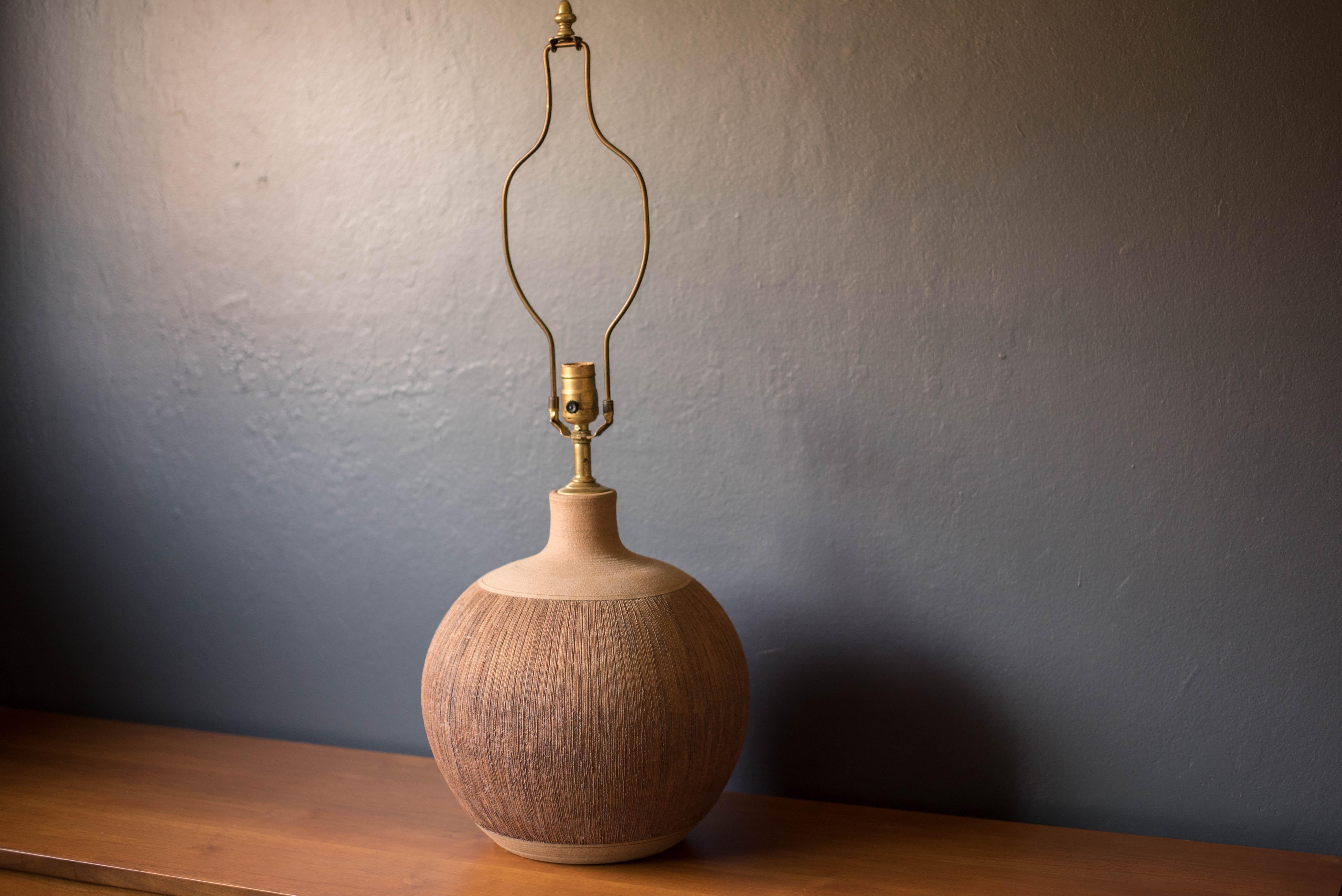 Mid Century ceramic pottery lamp signed 'Brown'. This handmade piece has an earth tone matte finish and is designed with an incised technique reminiscent of California artists such as Robert Maxwell and David Cressey. Includes original harp and