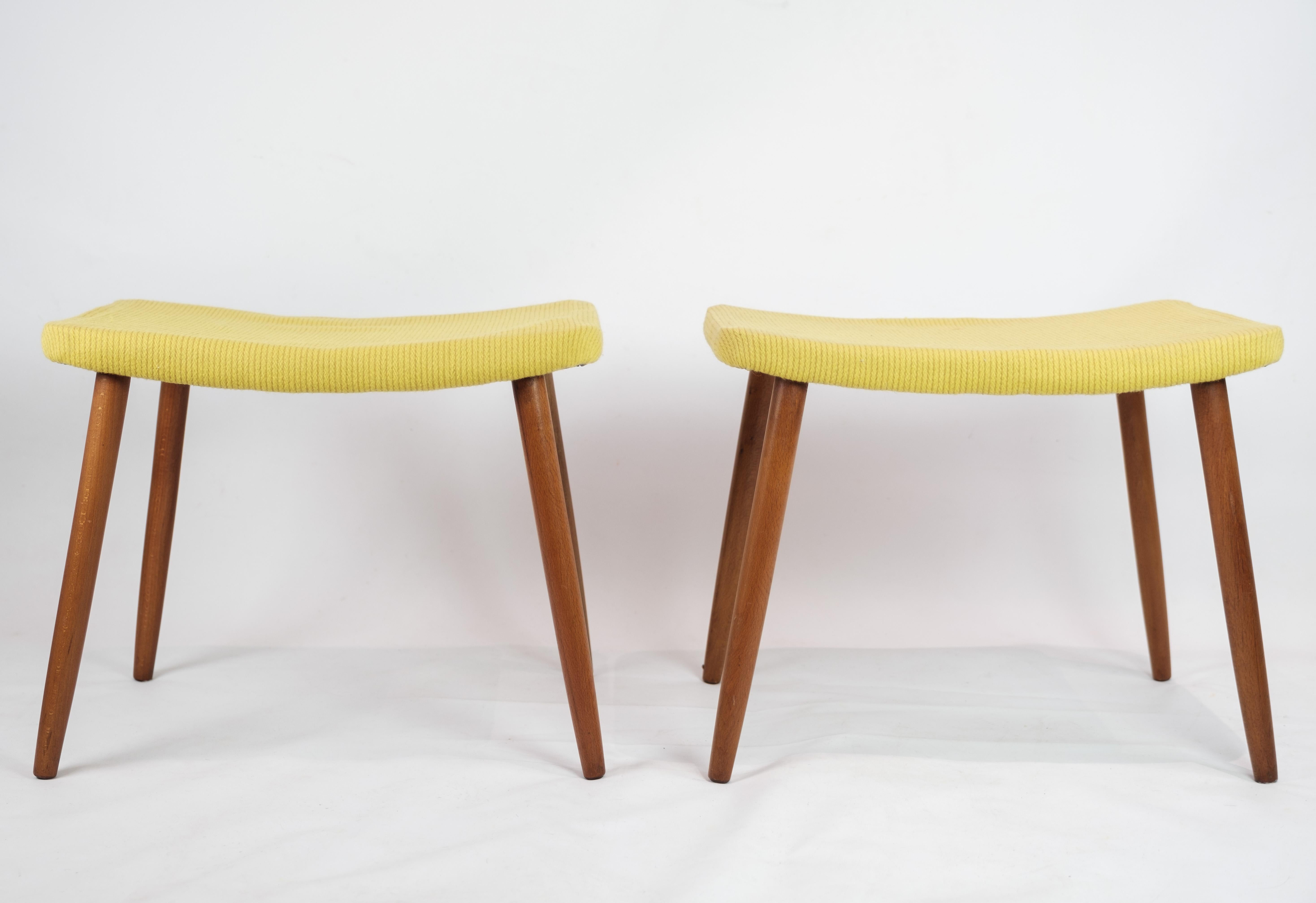This vintage stool exudes the quintessential charm of Danish design from the 1960s, showcasing a delightful combination of style and functionality. Adorned with vibrant yellow fabric upholstery and complemented by elegant teak legs, this stool adds