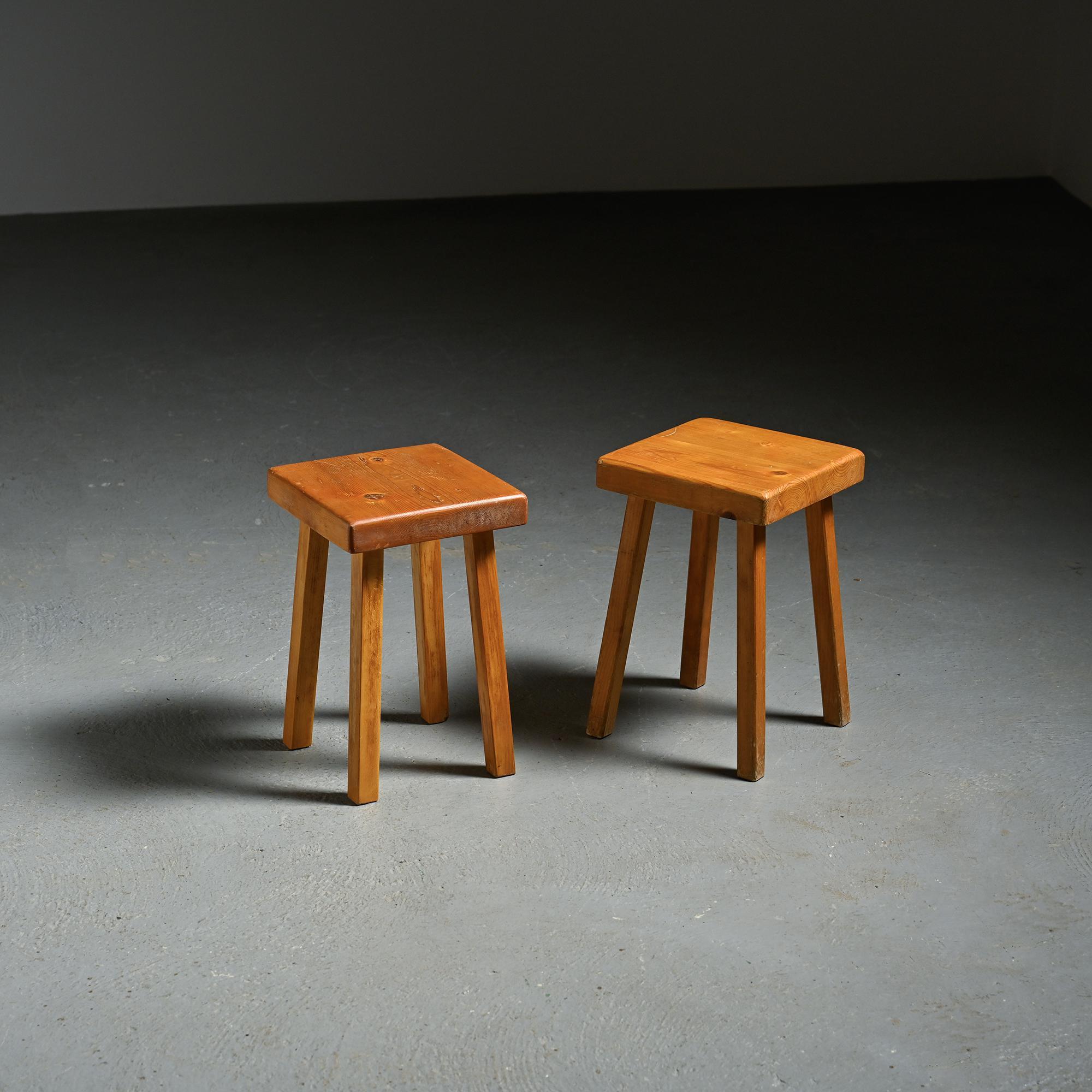 Pair of solid pine stools produced for the Les Arcs ski resort, a project to which Charlotte Perriand contributed for nearly twenty years. The square seat rests on a quadripod base with straightforward, sturdy lines, reflecting the utilitarian