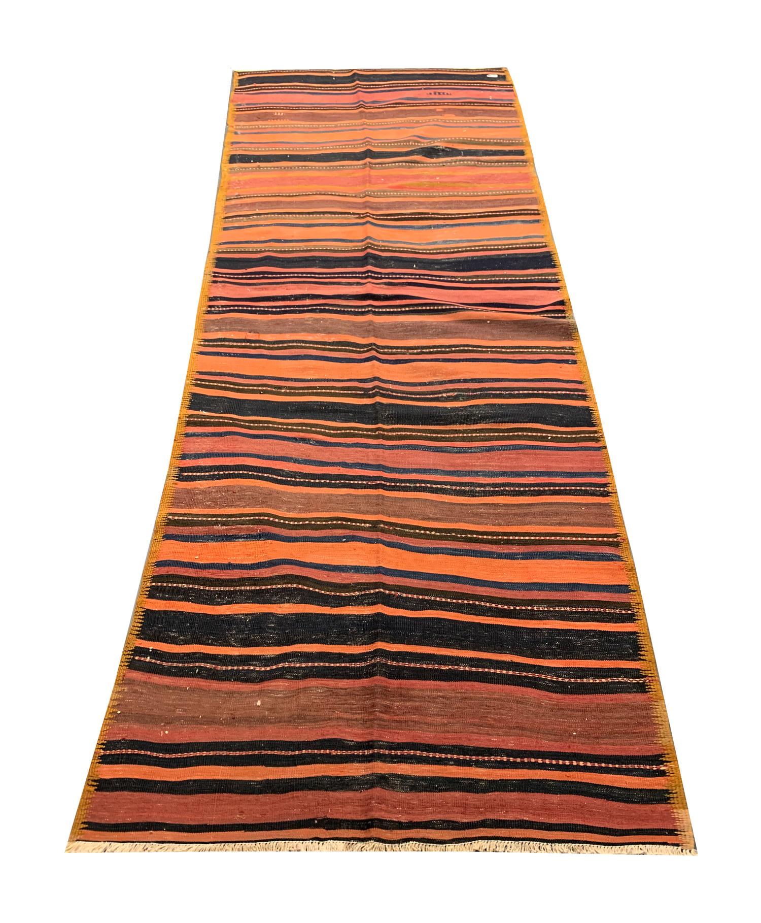 This beautiful striped antique Turkish Kilim was woven by hand in the late 19th century, circa 1890. The all over design features a simple yet eye-catching pattern with varying stripes of orange, brown, and black. 
The delicate design and beautiful