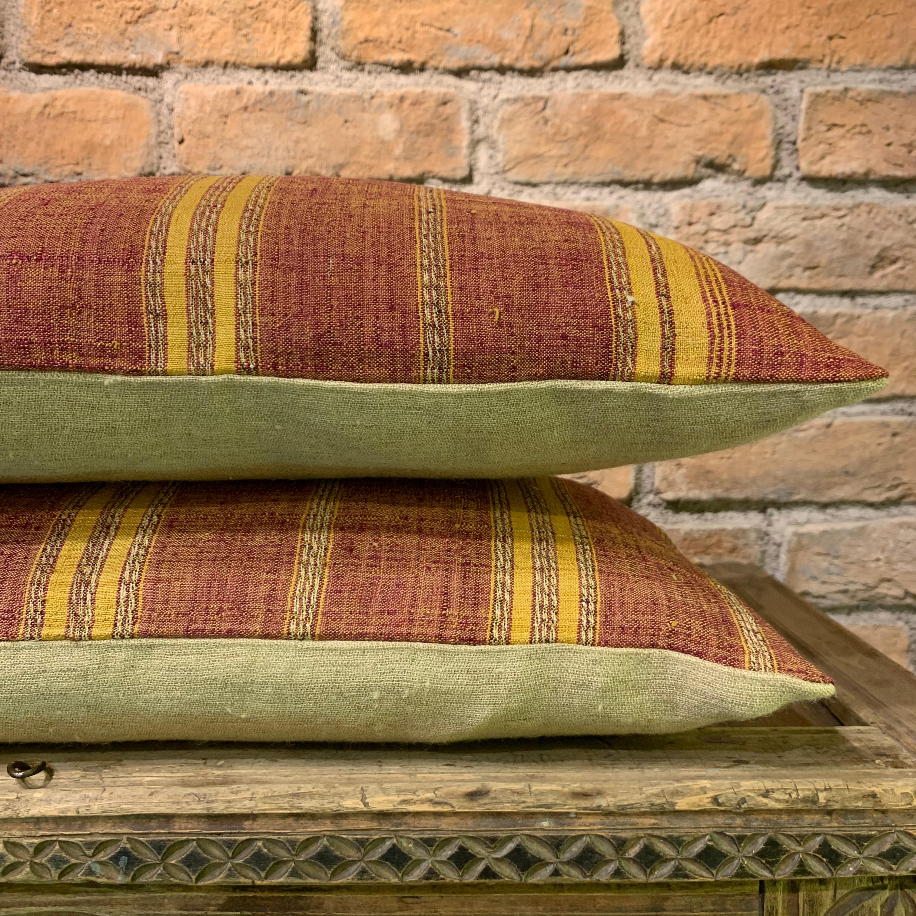 Questa sorprendente coppia di cuscini è realizzata con tessuti di seta vintage intrecciati a mano e provenienti dal Turkmenistan. L'audace fondo rosso è accentuato da strisce gialle dorate, che evocano il calore e l'eredità delle tradizioni nomadi