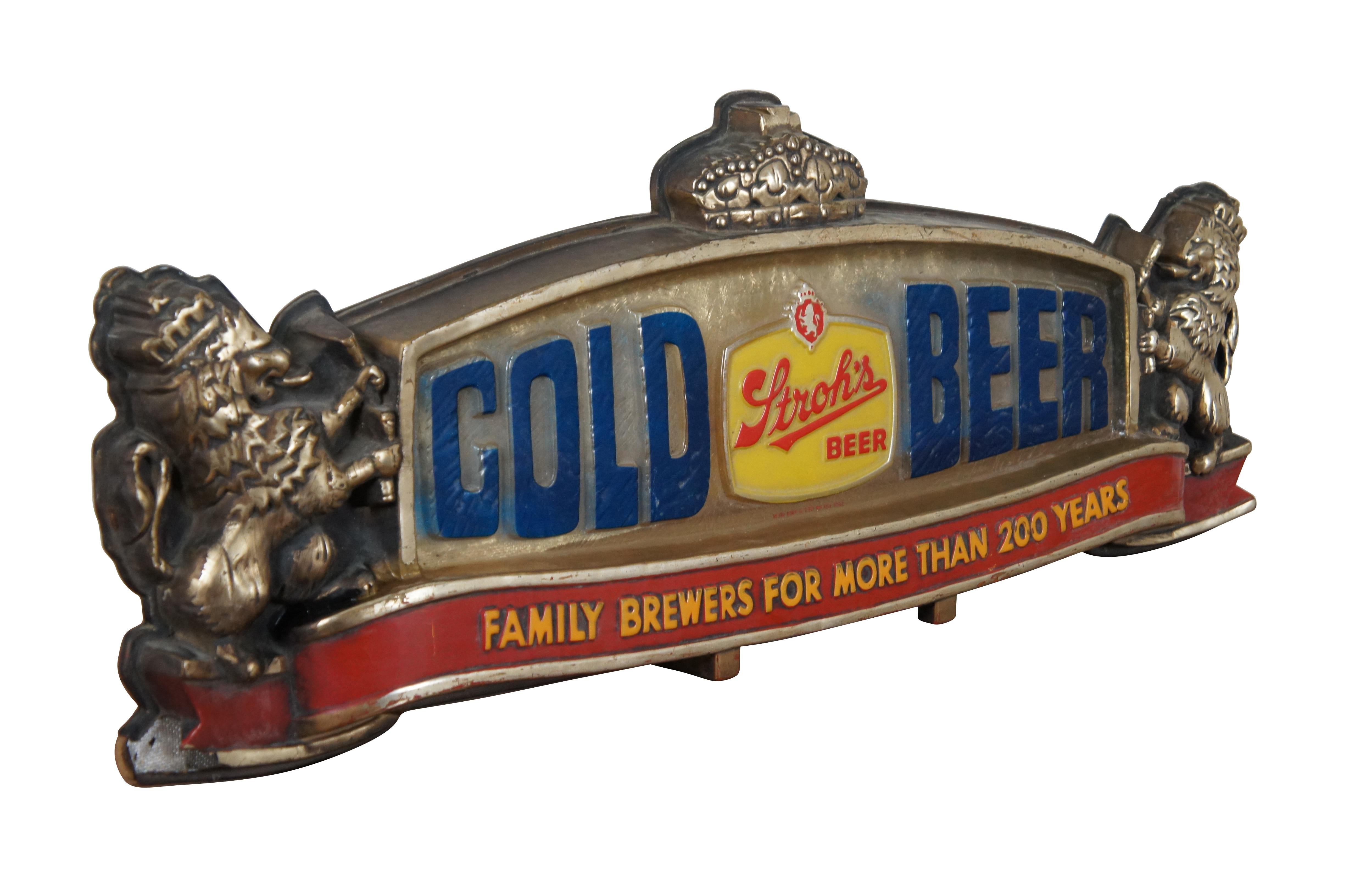 Vintage three dimensional plastic Stroh’s beer sign featuring the Stroh’s logo in yellow and red, flanked by the words “Cold Beer” in blue on a pebble surface, surrounded by a golden frame with a crown at the center of the top edge and held by a