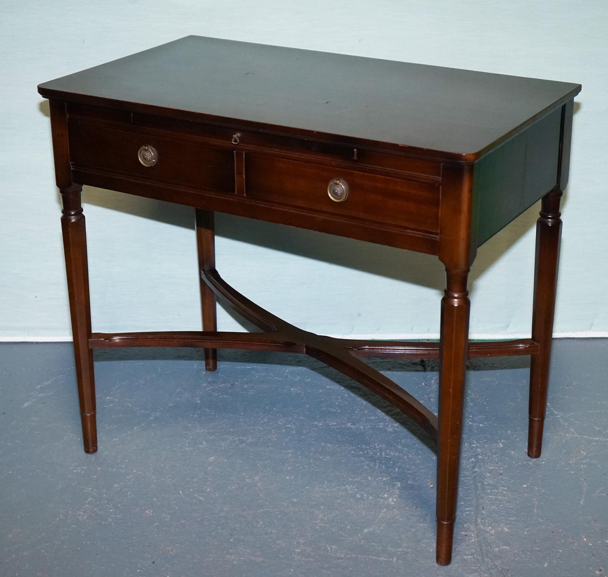 
Antiques of London



Discover this beautifully preserved Strongbow Furniture hardwood game table or writing desk, distinguished by its elegant cross-stretcher base and slender turned legs in the Regency / Mid‑Century Modern British style. Crafted