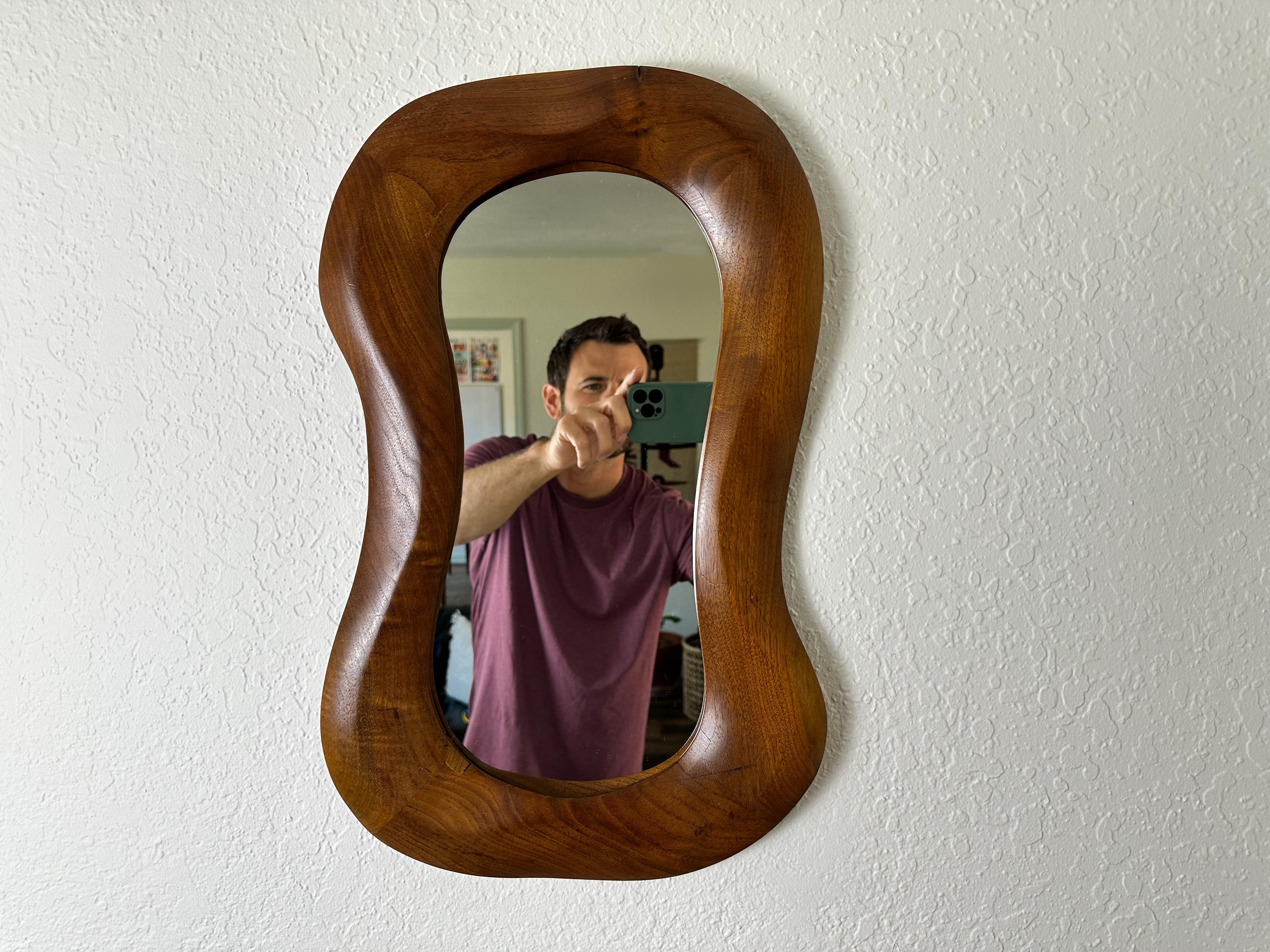 A whimsical, hand sculpted organic modern wall mirror. Made from beautiful old growth walnut with rich color and patina. Signed 'Reznik