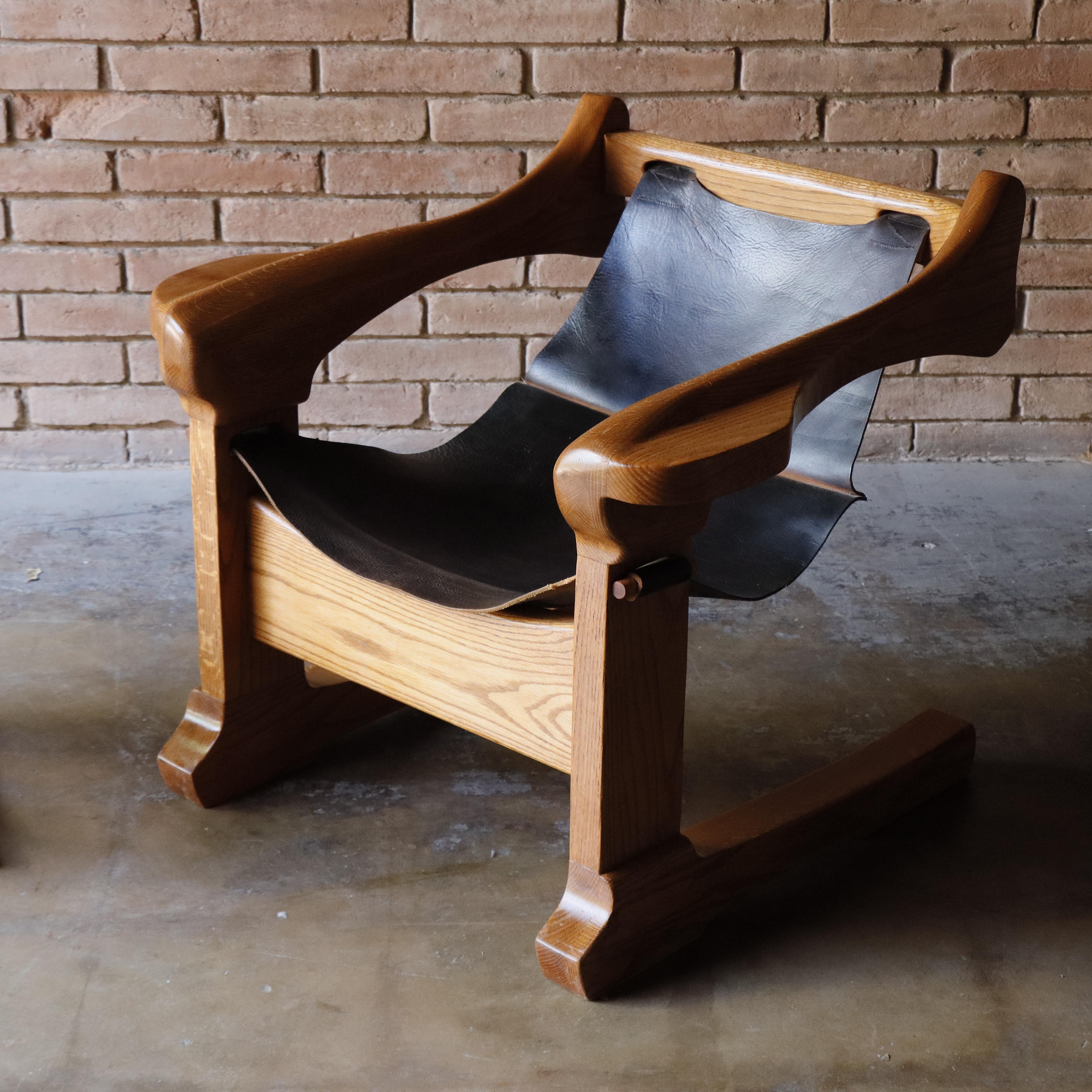 This striking studio-crafted cantilever chair from the 1970s channels the bold spirit of Mexican and Brazilian modernism mixed with American craftsmanship, 

Crafted from solid oak, the sculpted frame supports a suspended dark brown leather sling