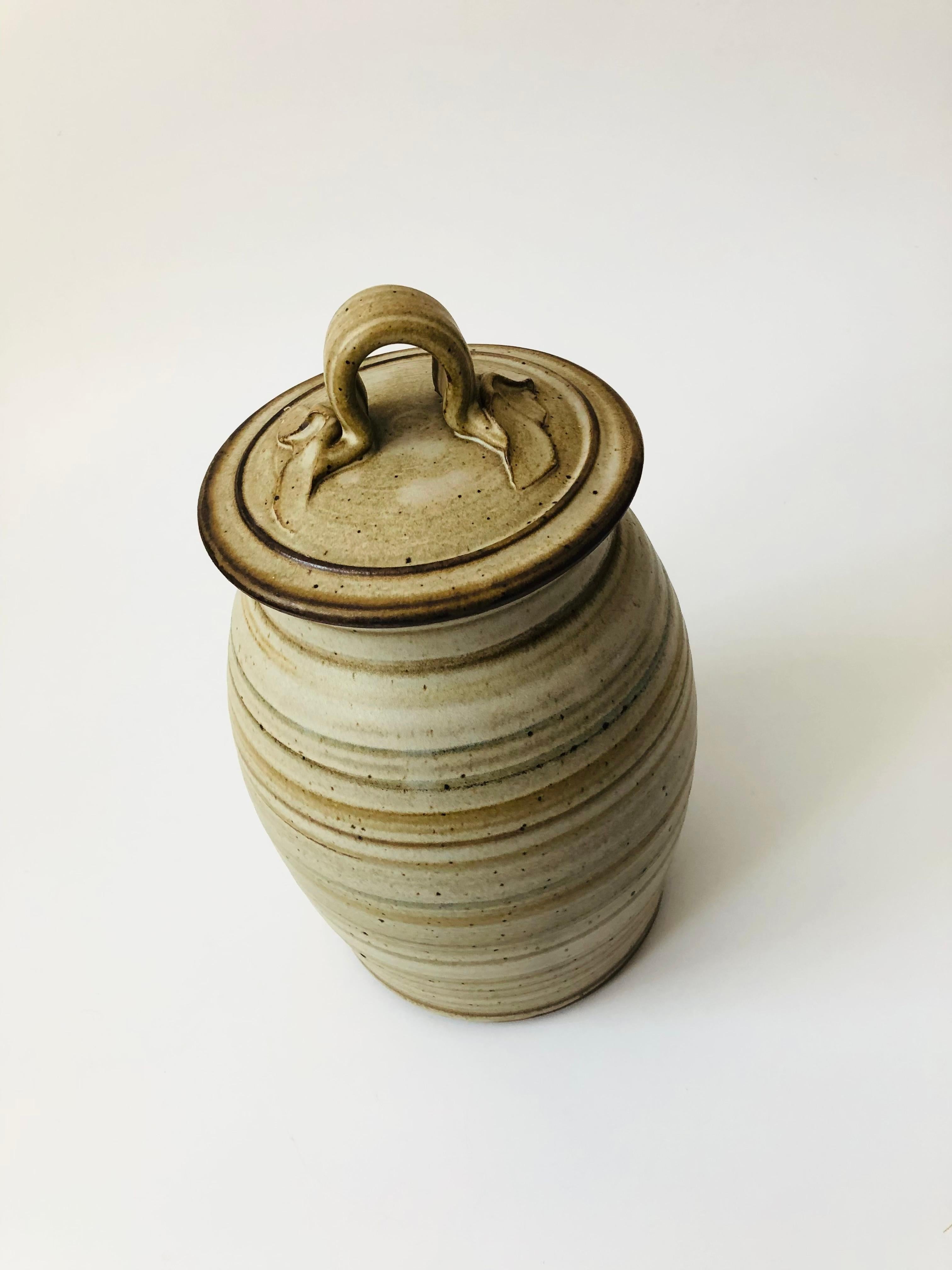 A vintage handmade studio pottery canister by artist Tim Wedel. Finished in a beautiful variety of interchanging bands of earth tone glazes. Great organic quality to the handle on the lid and a nice large size for storage. Signed on the base.