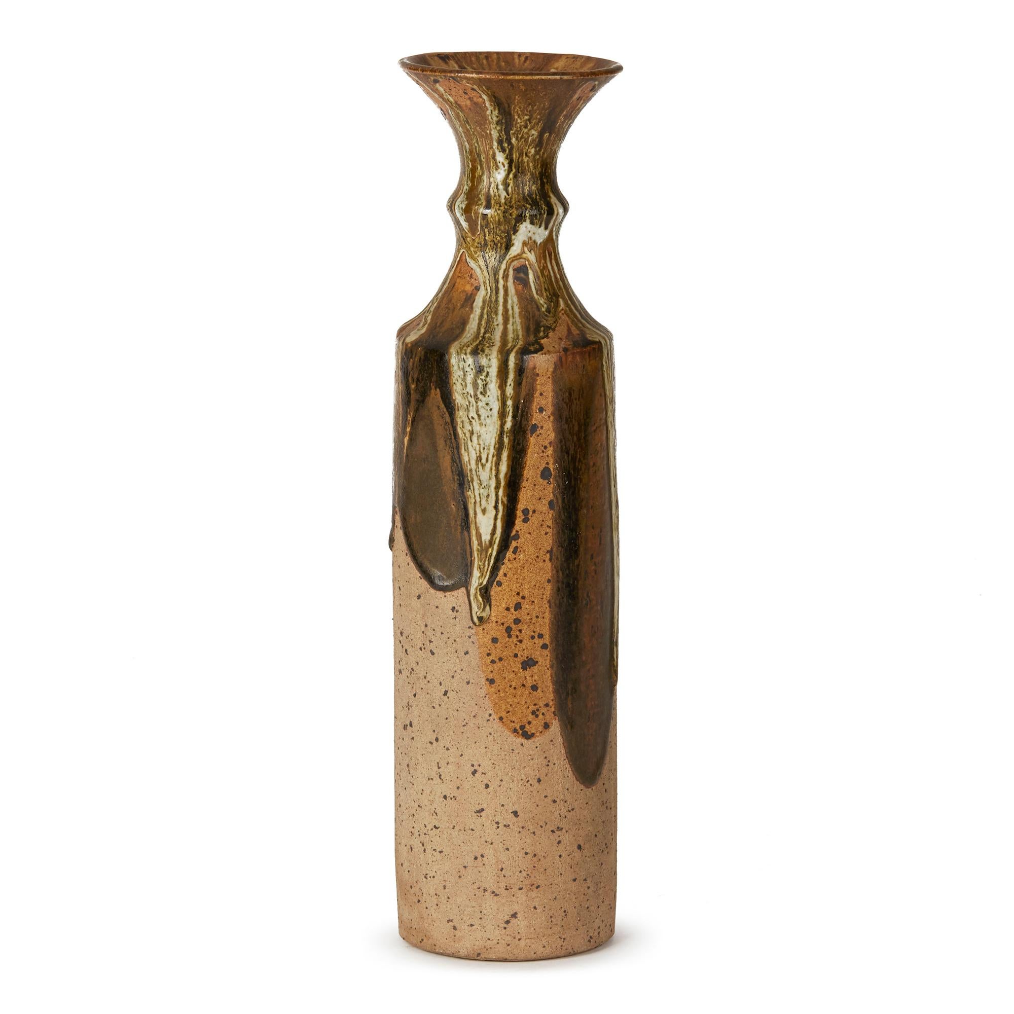 A large and impressive studio pottery stoneware vase of tall bottle shape with heaped and piled coloured drip glazes run down the body of the vase over brown glazed panels set with an unglazed ground. The vase has a trumpet shaped top and has two