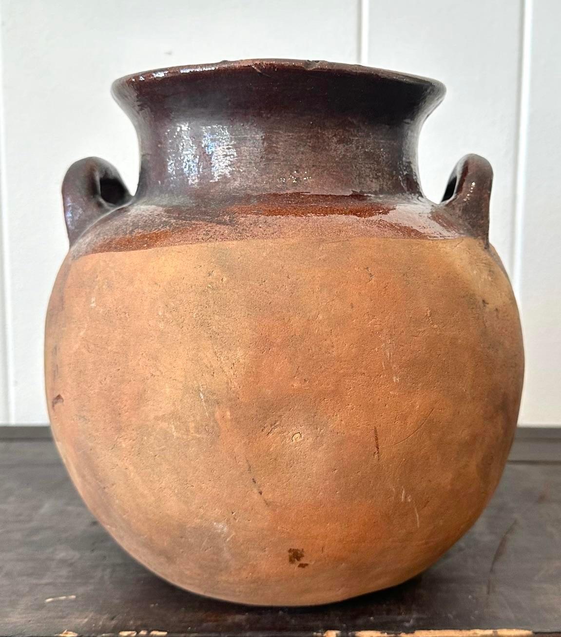Introduci un fascino rustico nel tuo arredamento con il Vintage Studio Pottery Half Glazed Vase With Handles. Questo pezzo artigianale è caratterizzato da un'esclusiva finitura semilucida e da manici robusti, che incarnano la qualità artigianale