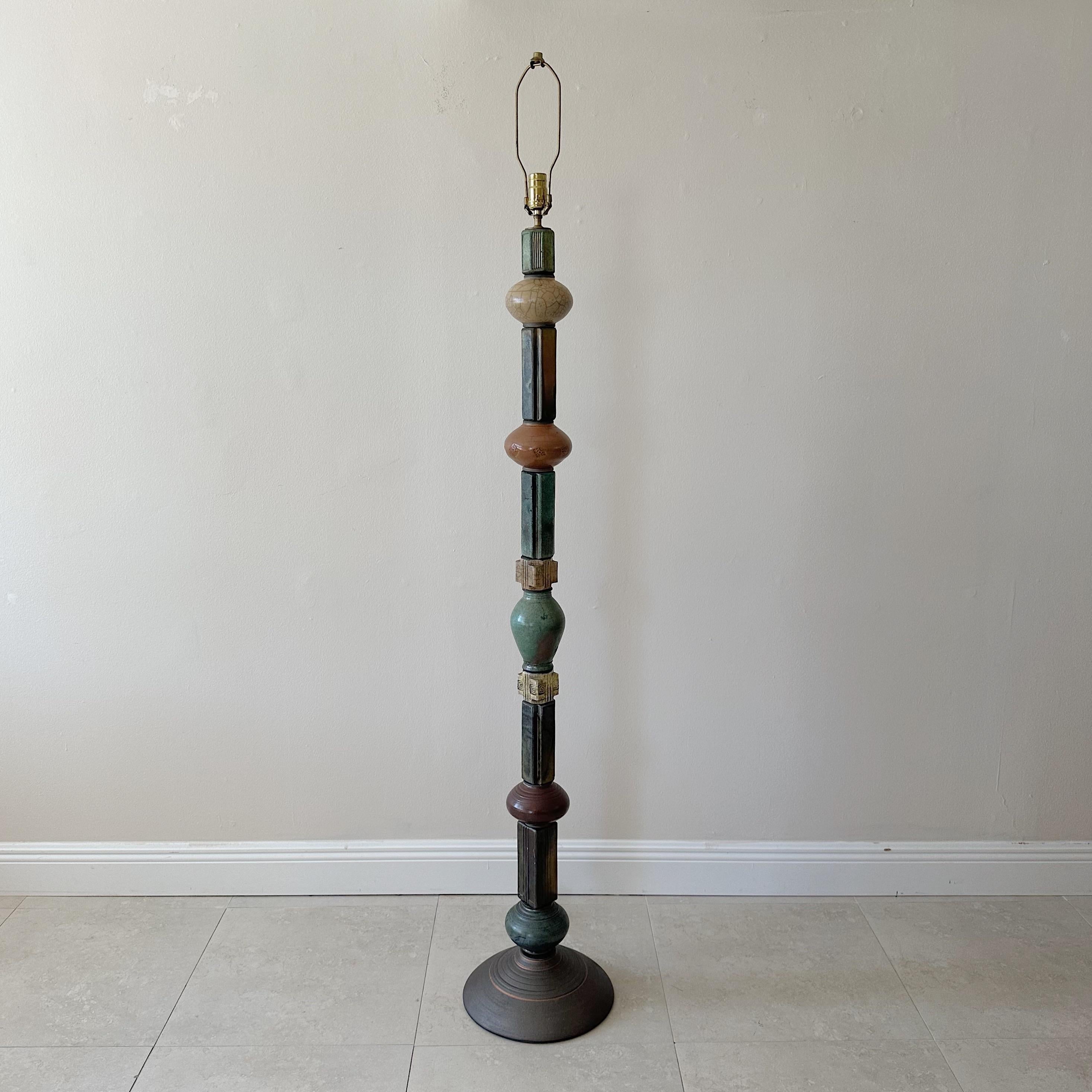 This is a one-of-a-kind floor lamp made up of 13 distinct pottery pieces arranged on a single stem. Each piece features its own intricate decoration and color scheme, giving the lamp a striking and personalized appearance. The lamp is signed on the