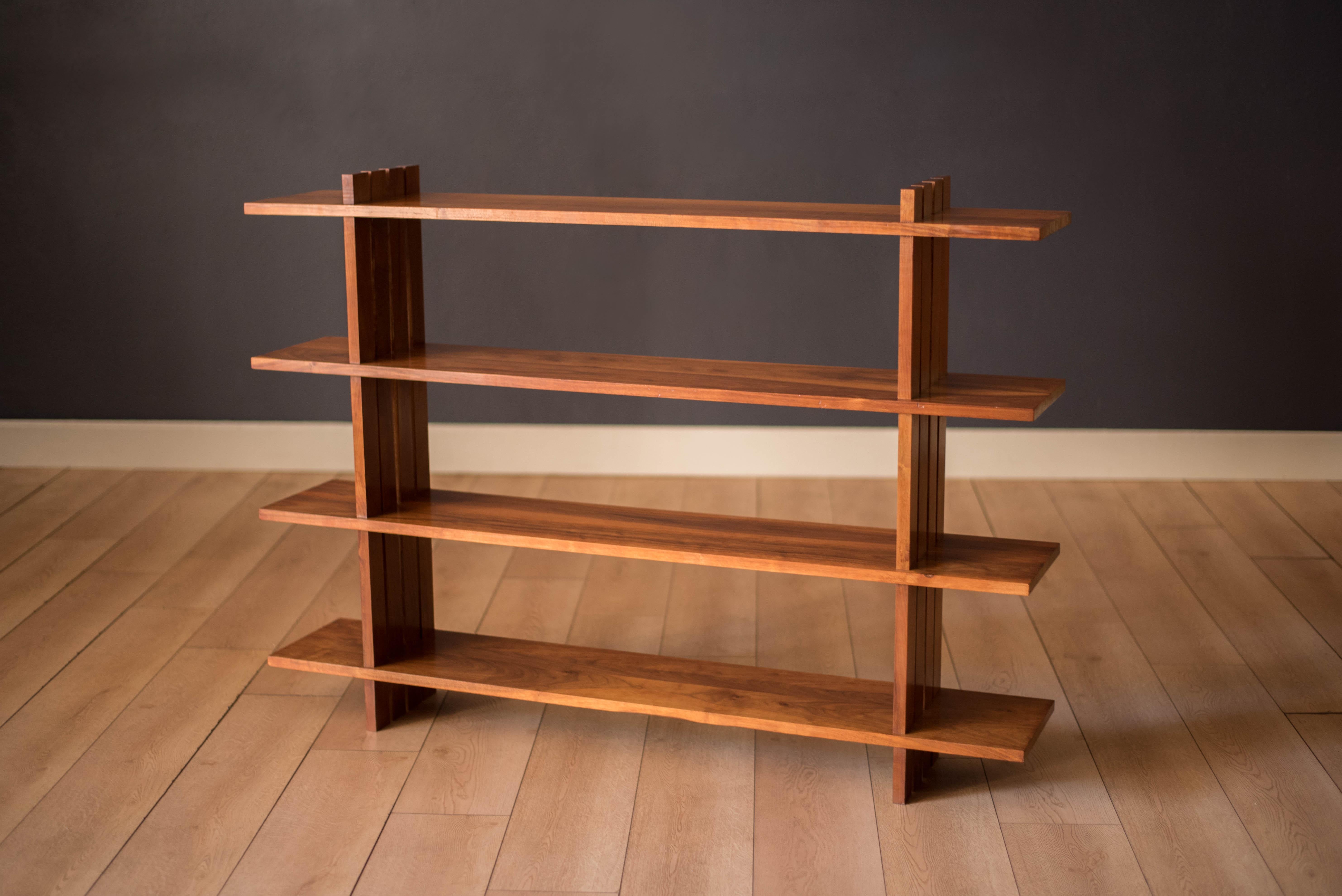 Mid century modern bookcase shelving system studio made circa 1960s. This organizing bookshelf provides plenty of storage with four tiers of open shelving that showcases from all sides. Constructed of solid natural walnut, this piece also serves as