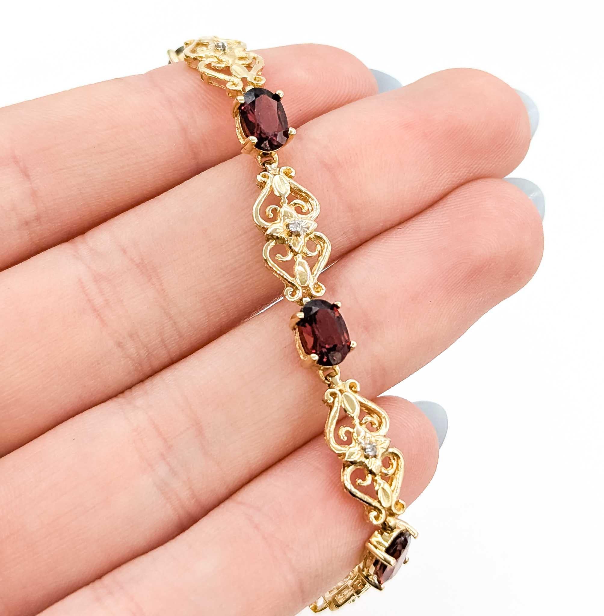 Cet élégant bracelet est réalisé en or jaune 10k et conçu avec un motif filigrane d'inspiration vintage. Il comprend 6,40 carats de grenats ovales richement colorés, chacun solidement serti entre des maillons ajourés complexes rehaussés de diamants