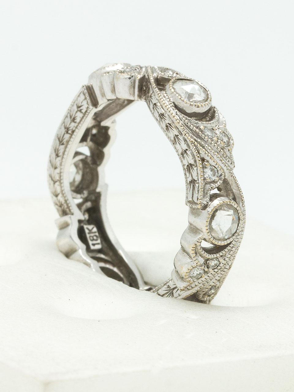 18K White gold & diamond vintage style eternity band set with six bezel set rose cut diamonds & 18 bead set round diamonds in a floral design. Approximate total of 0.60ctw. 5mm wide, Size 6, unable to adjust. Circa 2000s.

SKU: 37204