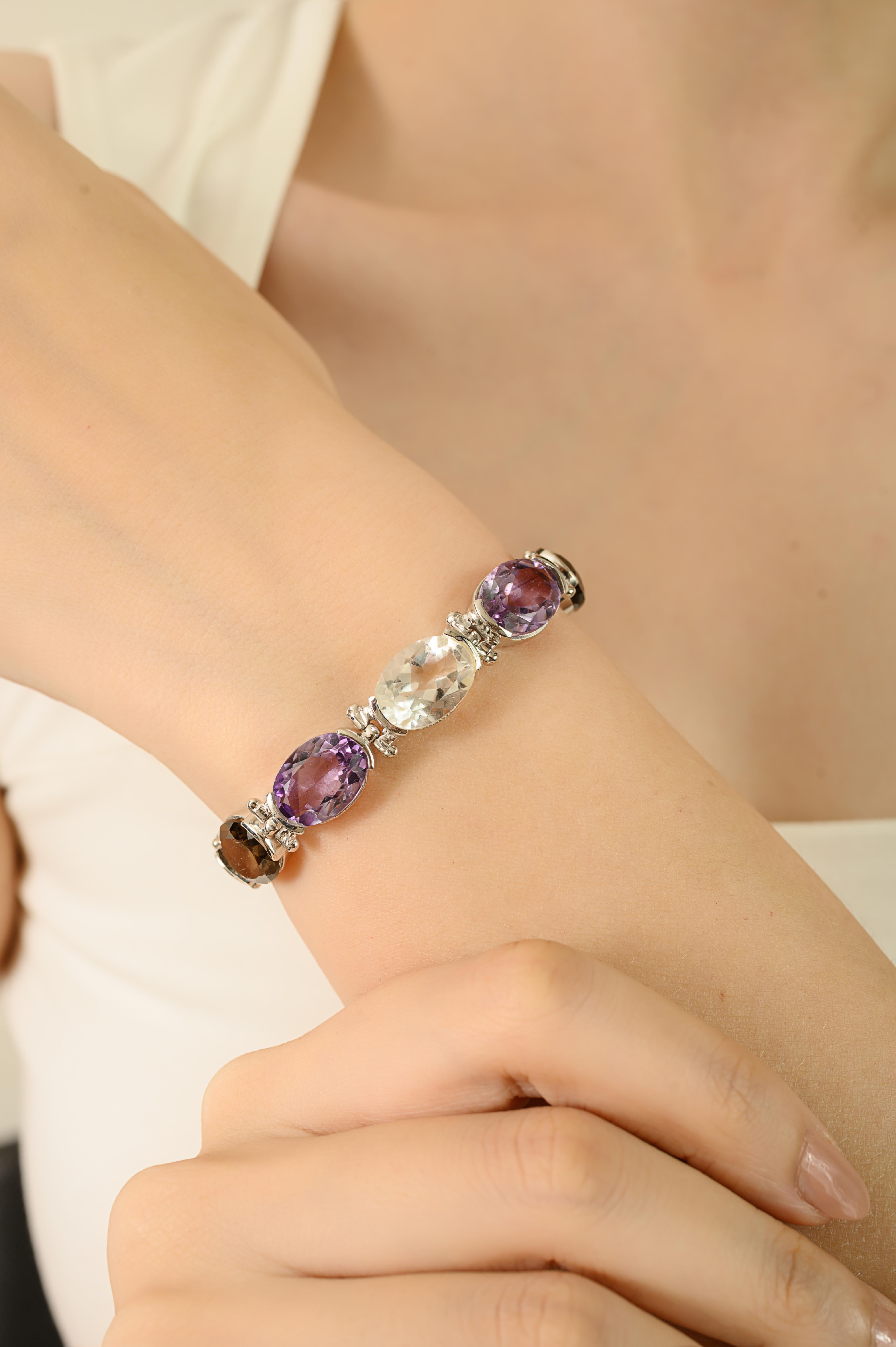Questo bellissimo bracciale presenta un mix di tre gemme: Ametista, Quarzo limone e Quarzo fumé. Ogni pietra è tagliata in forma ovale liscia, nelle dimensioni di 12x10 mm e 6x5 mm, per un peso totale di 27,5 carati. Tutte le pietre sono incastonate