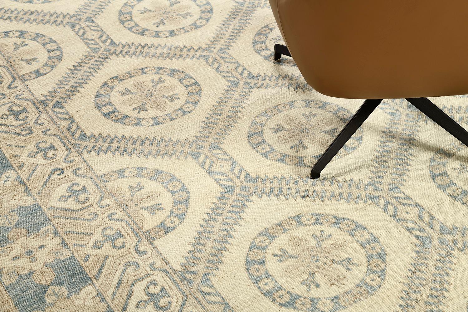 An astounding recreation of Arts and Craft style rug that features the elegant tones of blue and sand. Fabricating gracefully in an ivory field, the geometrical pattern and ornamental embellishments are formed flawlessly enclosed by a classy border
