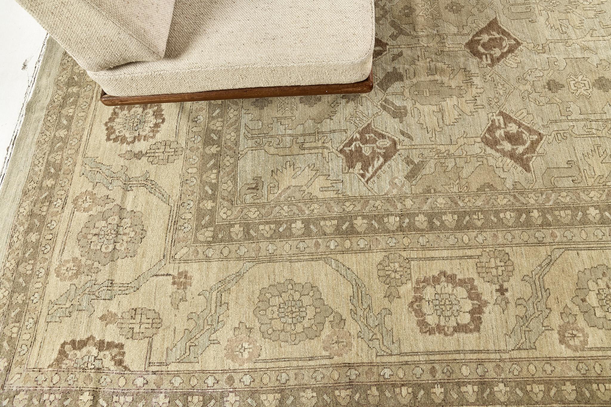 A breathtaking muted revival of Bakhshaish design rug that combines the stunning palmettes and statement vines connected by the leafy tendrils in the shades of sand, dusty blue and brown. This exquisite rug has a magical presence provided by the