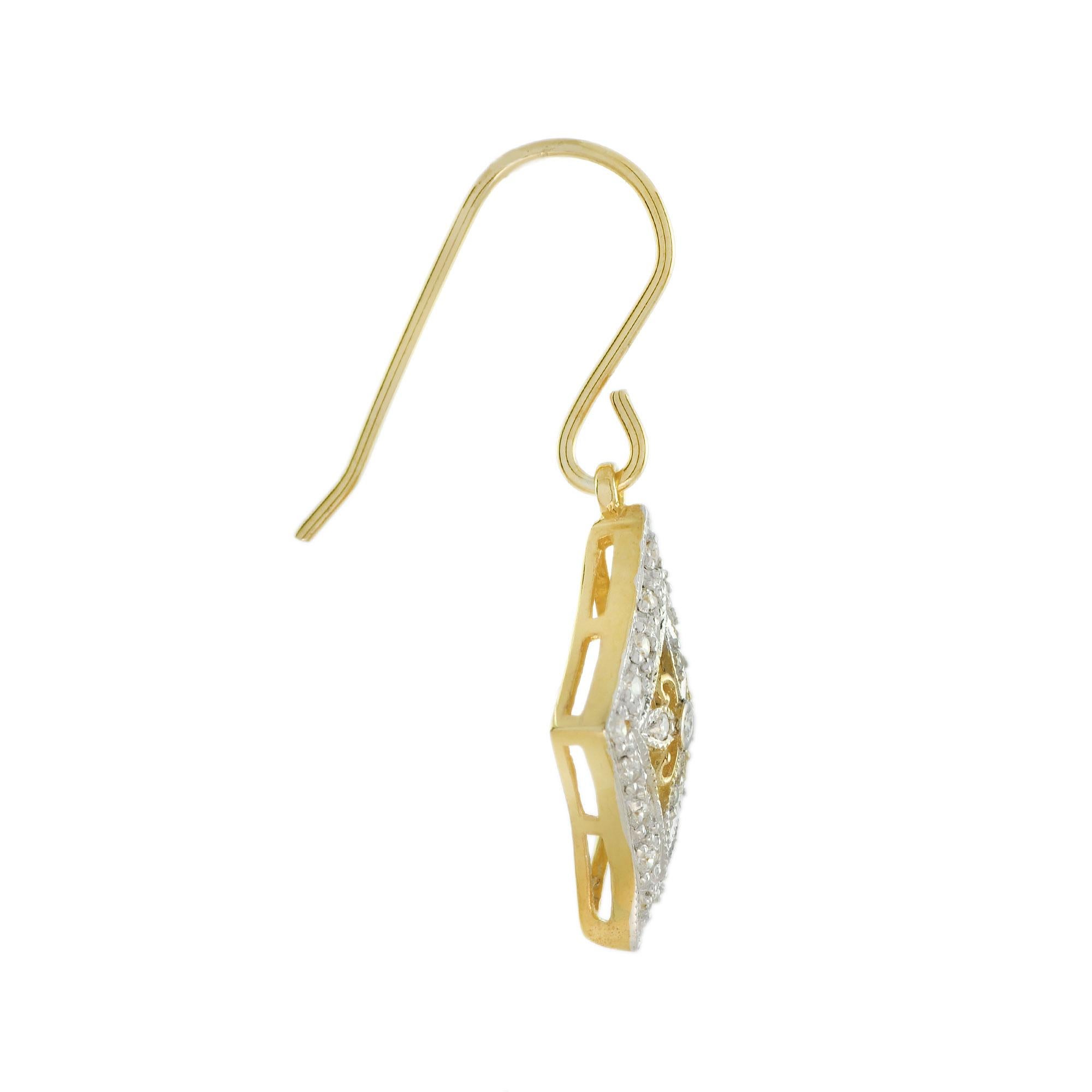 Vintage design feminine earrings of 14k yellow gold with white rhodium to highlight the diamonds. The diamond shaped outer border surrounds a central floral cluster design, all suspended from a French wire earrings to catch the light with your every