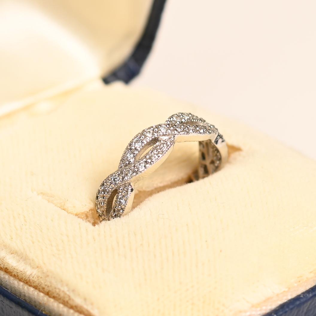 Esta exquisita alianza infinita de estilo vintage es un verdadero testimonio de elegancia atemporal y artesanía experta. Diseñada para simbolizar el amor eterno, la banda presenta un elegante diseño infinito entrelazado, meticulosamente adornado con
