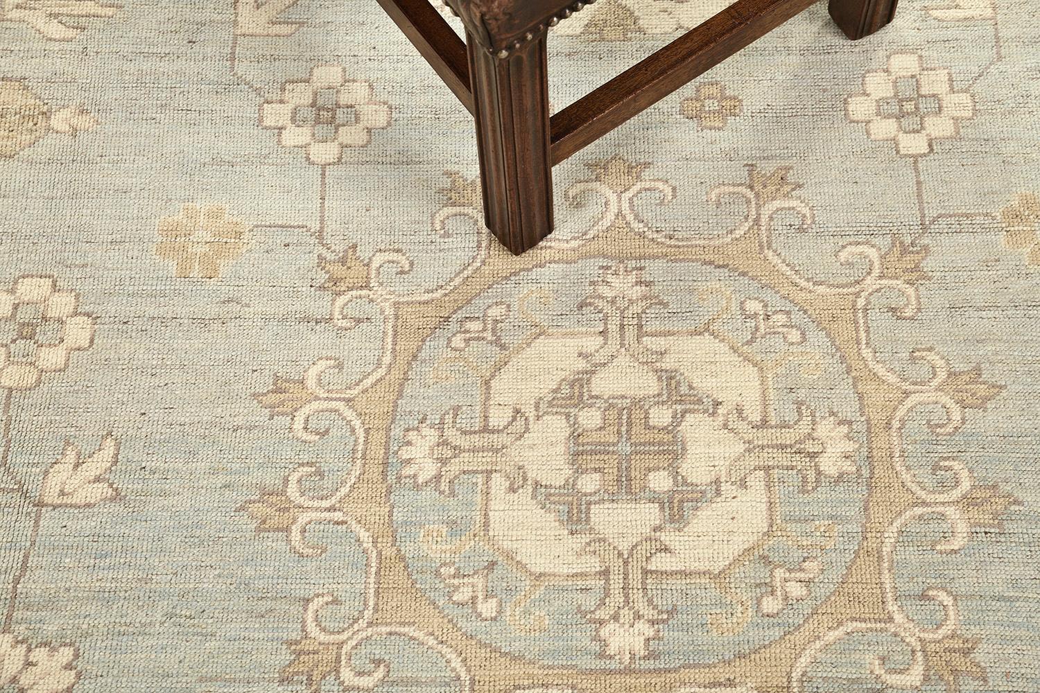 A meticulous revival of a Khotan Design rug, ideally suited for a floor wall piece. Three grandiose medallions and symmetric motifs in camel tone outlines are aligned that have spaces in a muted blue field. From borders to the field, it compliments