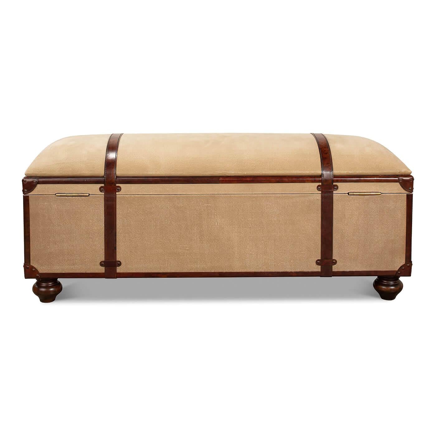 A vintage-style leather and canvas trunk bench. This bench is wrapped in beige canvas and has leather-wrapped edges and corners with brass. Inspired by the look of a vintage luggage travel trunk, it has leather strap accents going from front to back